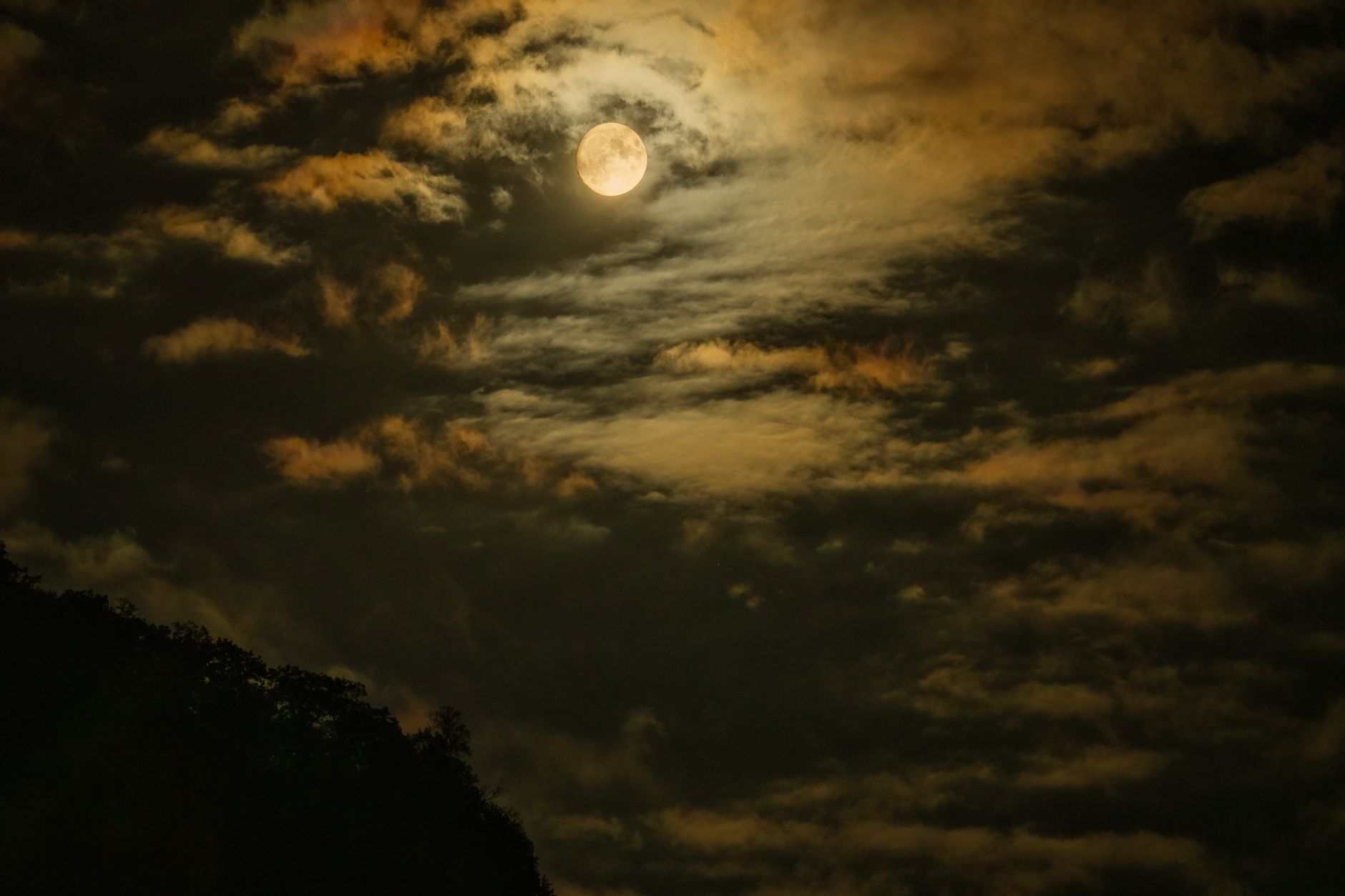 A bright full moon rising over a dark landscape, symbolizing the Capricorn Full Moon on June 29th