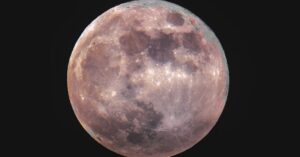 Large full moon rising against a dark blue night sky