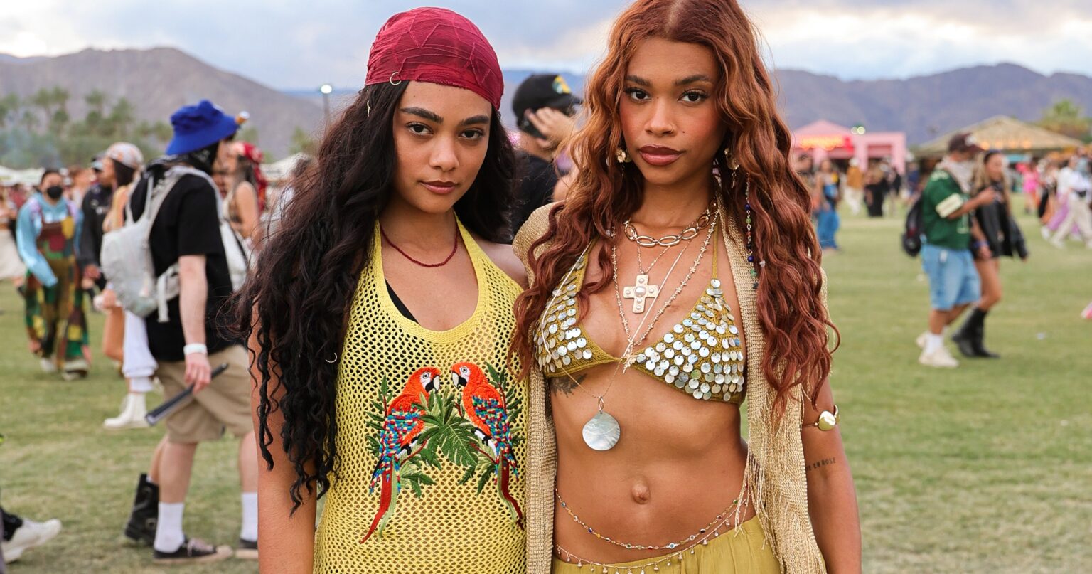 Festival crowd in desert setting with colorful outfits and wide-brim hats