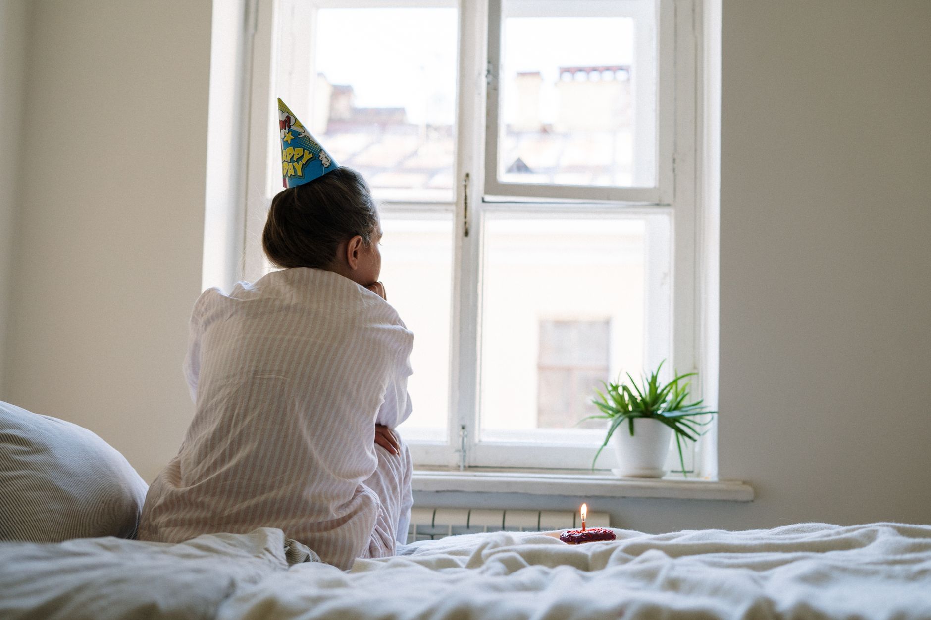 Woman sitting alone at a table with a single candle, quiet birthday moment