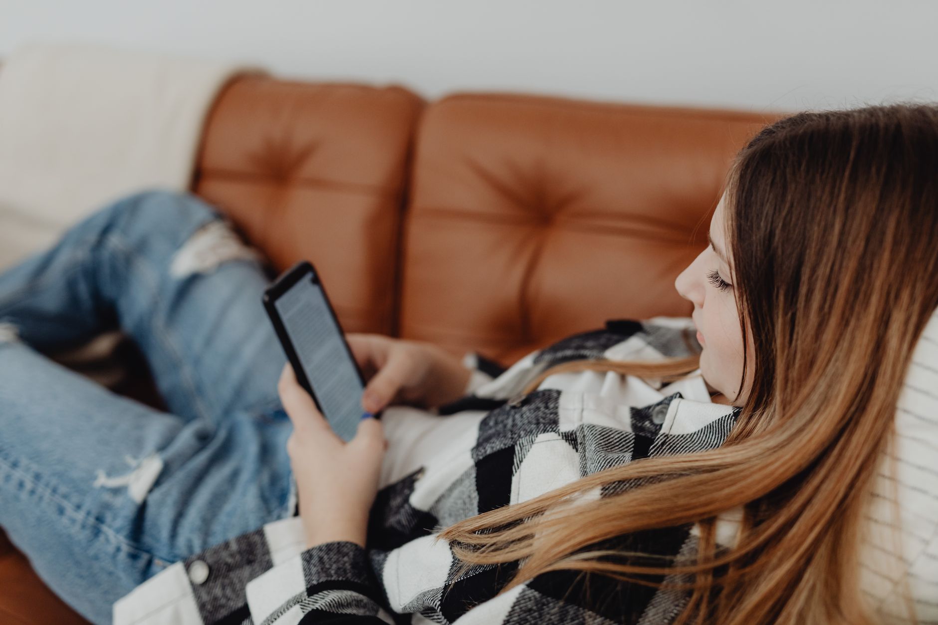 Woman sitting alone looking at her phone with a thoughtful expression
