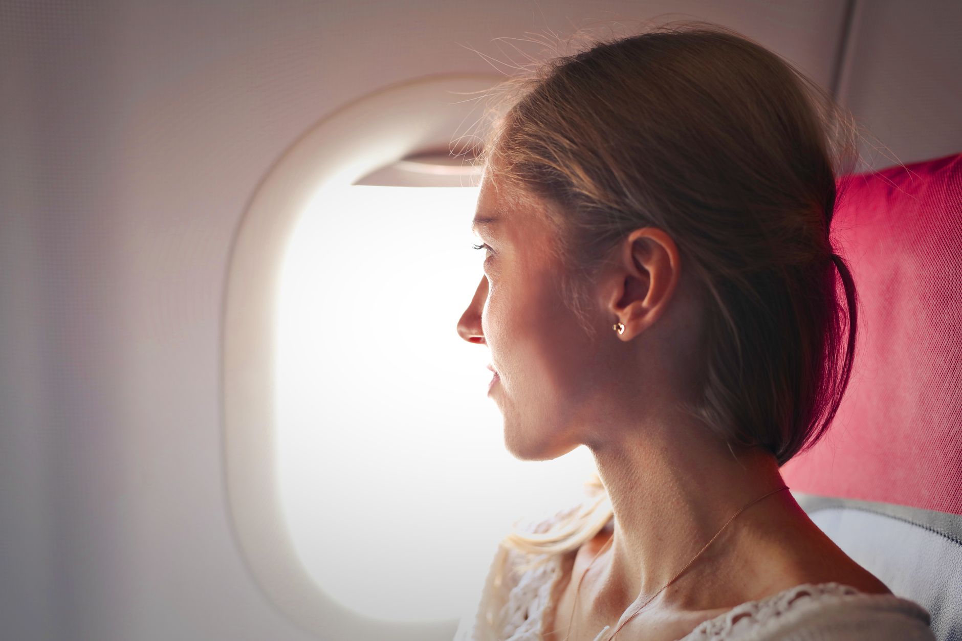 Passenger resting near an airplane window during a flight