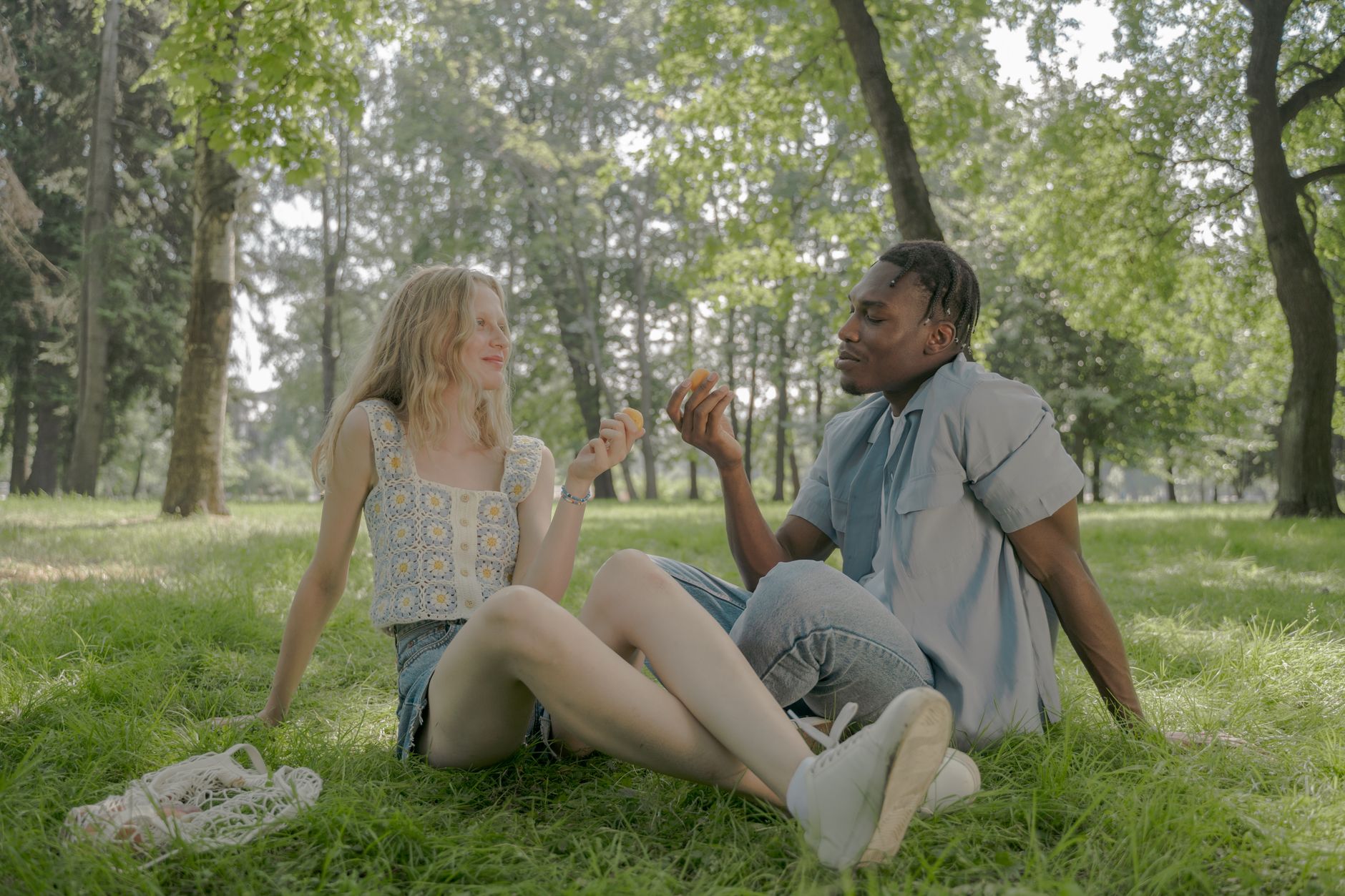 A couple sitting together in a park on a sunny afternoon with wine glasses