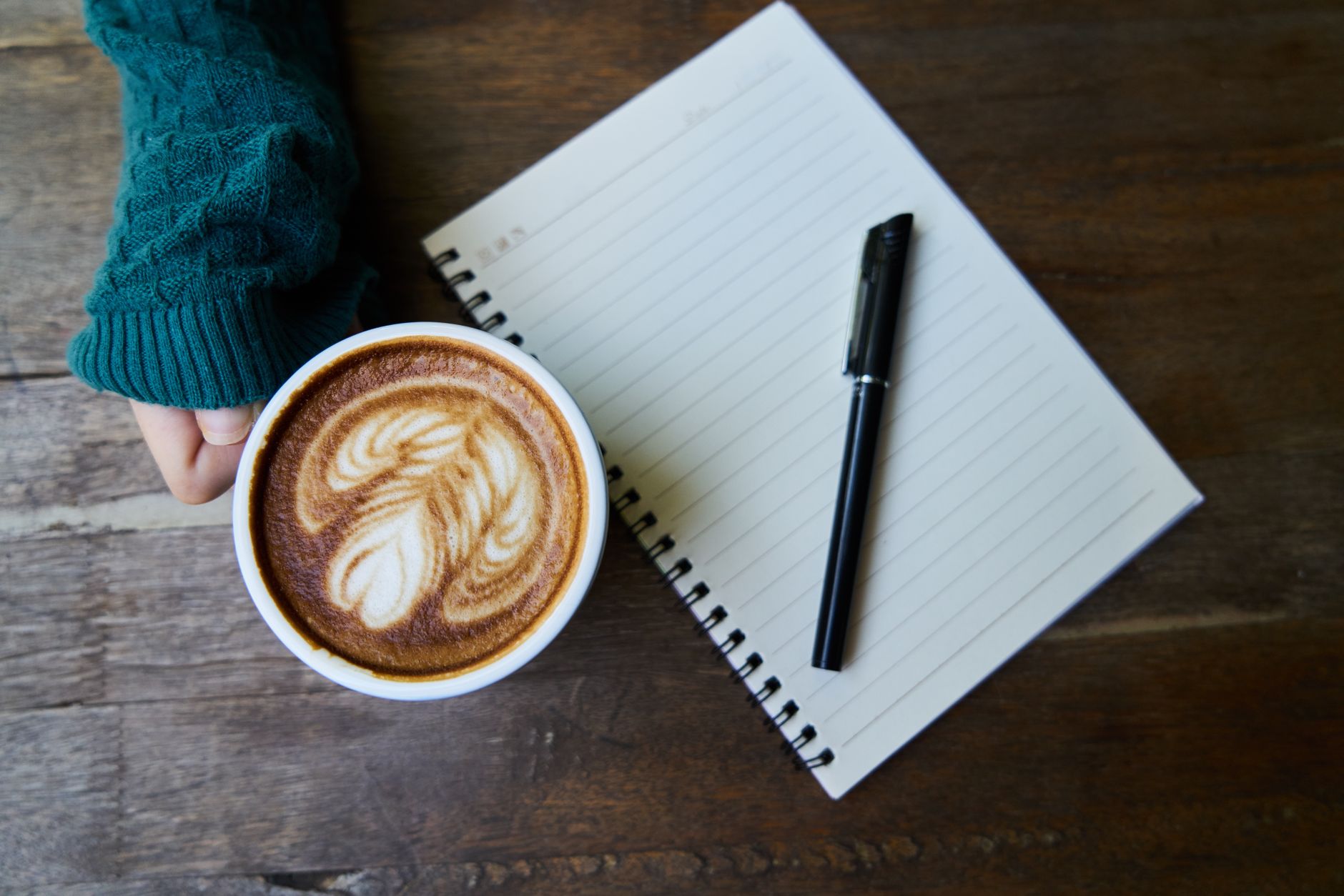 Person sitting quietly at a table with a notebook and morning light