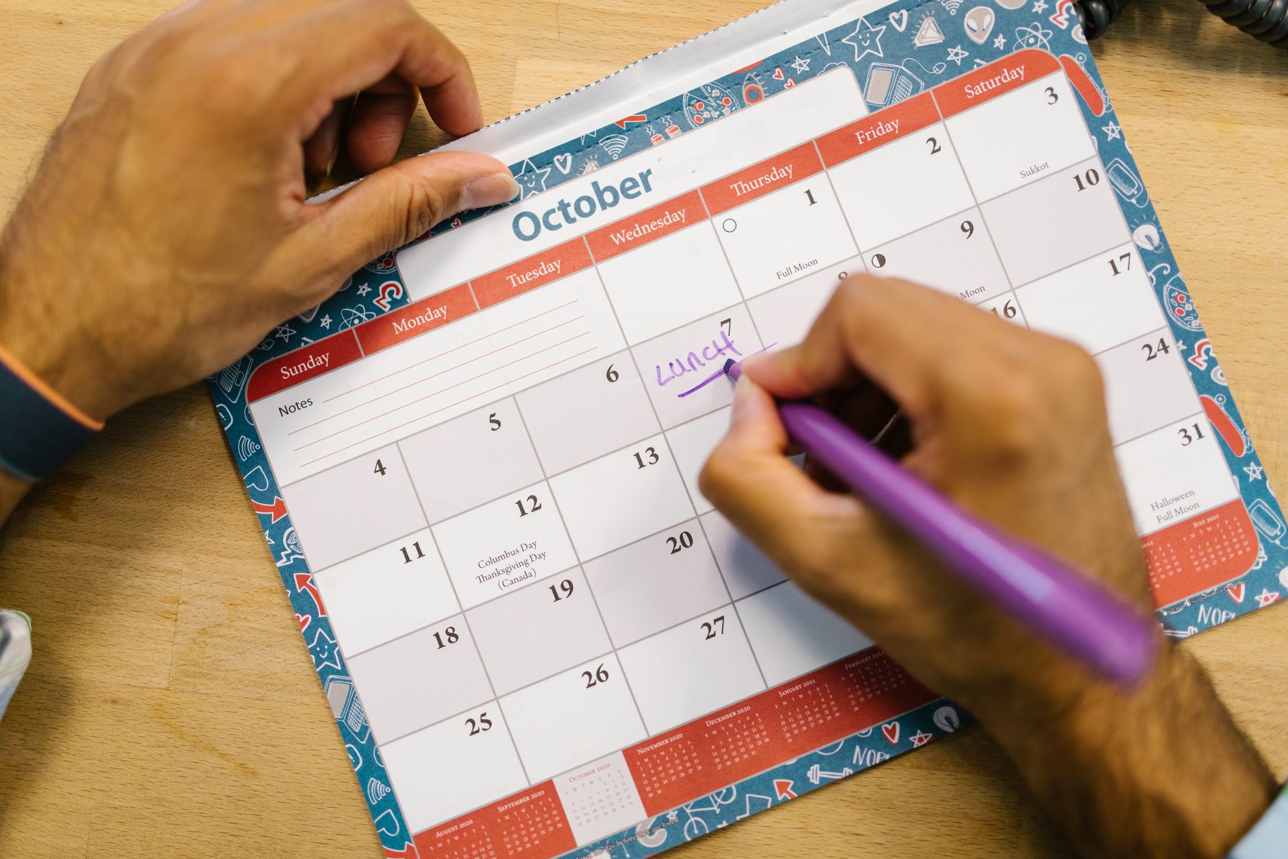 Open planner on a desk with a pen beside it