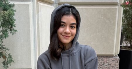 The Hoodie With a Built-In Eye Mask That Won February Person wearing a grey hoodie in a relaxed travel setting