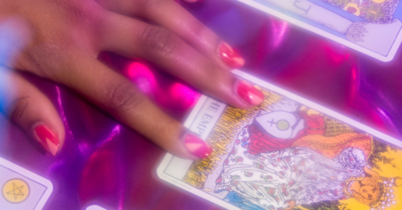 Your July Tarotscope Will Help You Trust Yourself Again Tarot cards spread on a wooden table in soft natural light