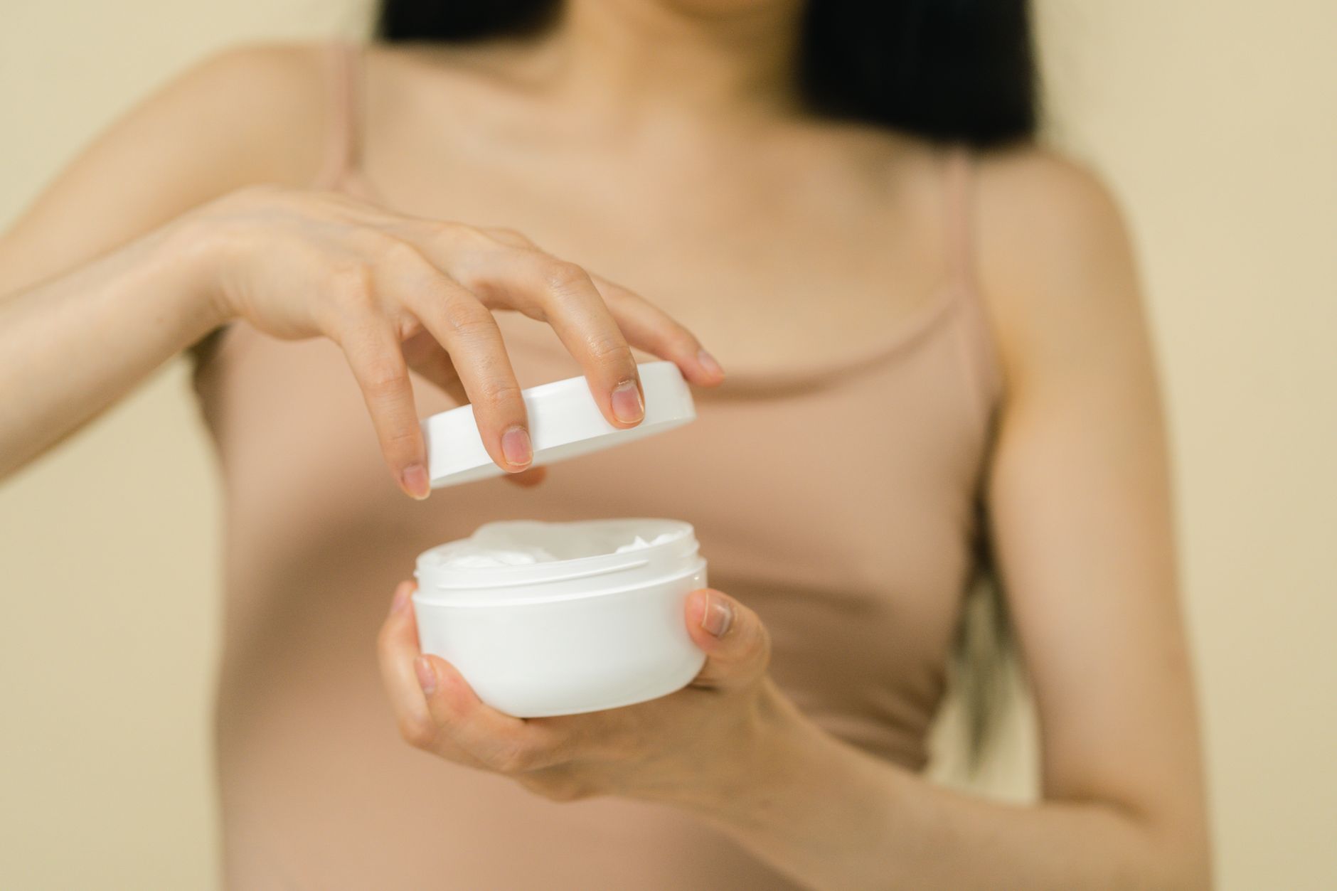 Close-up of an open white cosmetic cream jar on a light surface