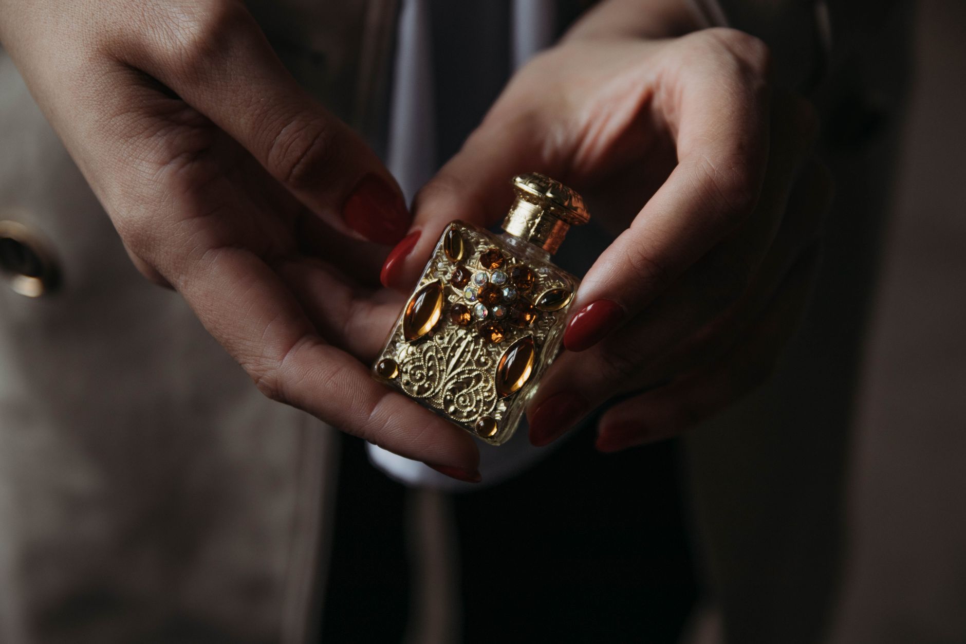 Elegant glass perfume bottle with dark liquid on a reflective surface