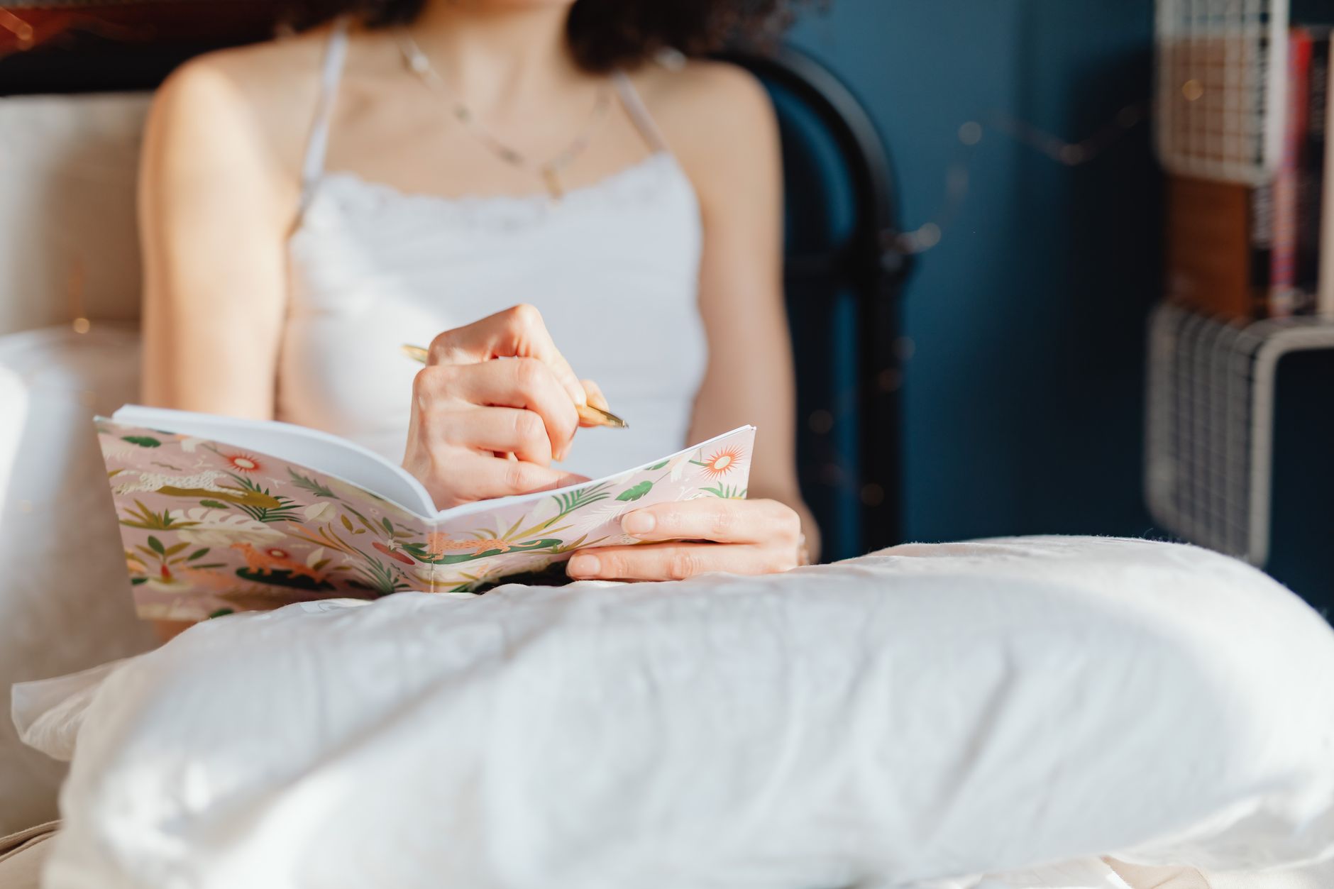 A woman writing in a journal at a sunlit table during a quiet morning