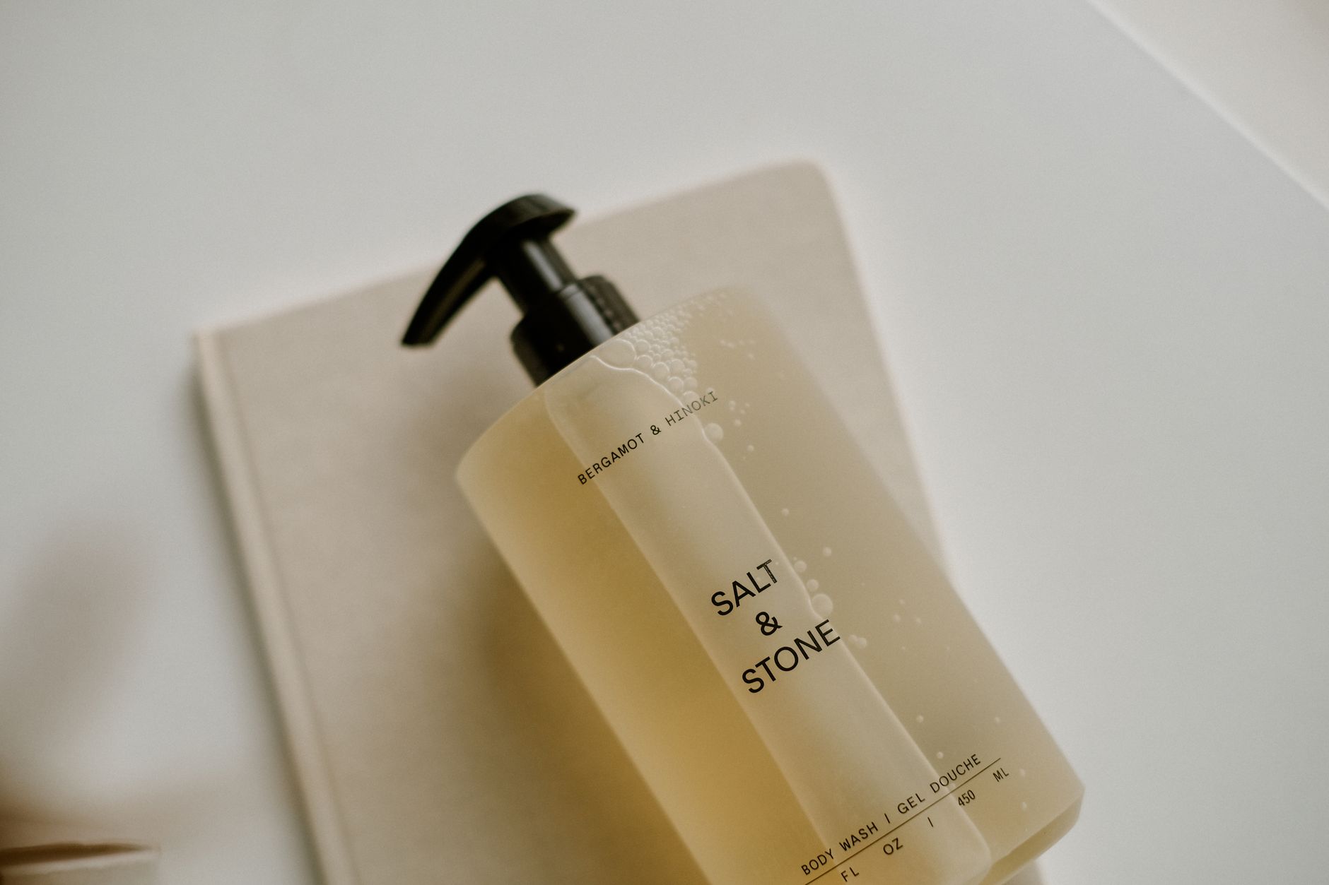 Elegant body care products arranged on a marble surface in a minimal bathroom setting