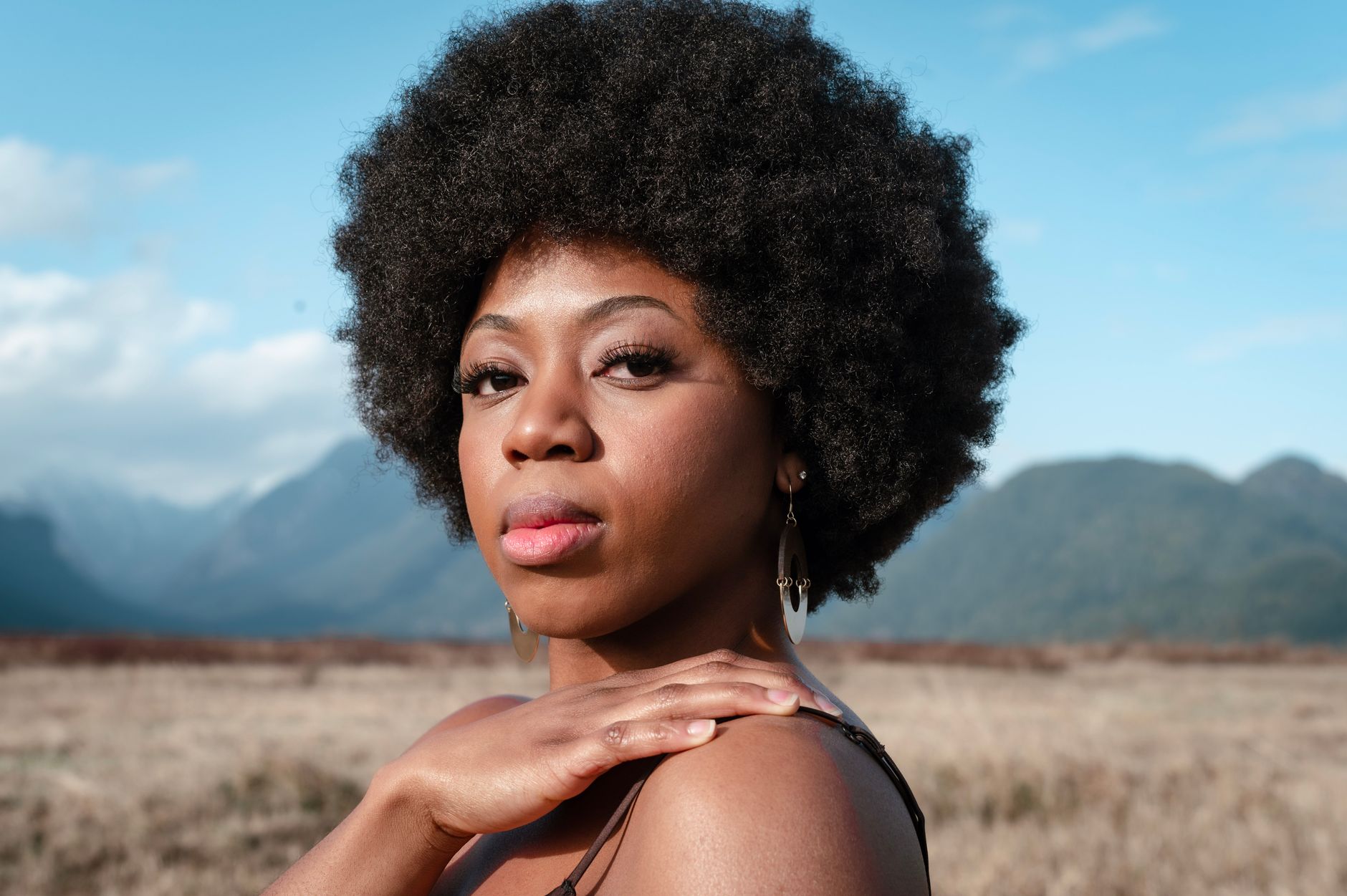 A woman wearing natural afro hair at medium length, well-shaped and textured