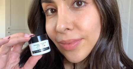 A $16 Eye Cream Changed My Mind After Years of Skepticism Woman applying eye cream in front of a bathroom mirror during a morning skincare routine