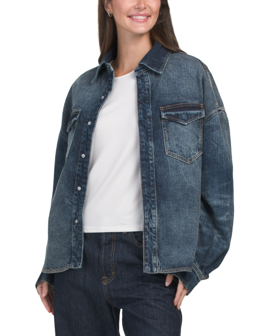 A woman wearing a relaxed denim outfit with sneakers and layered accessories in an autumn setting