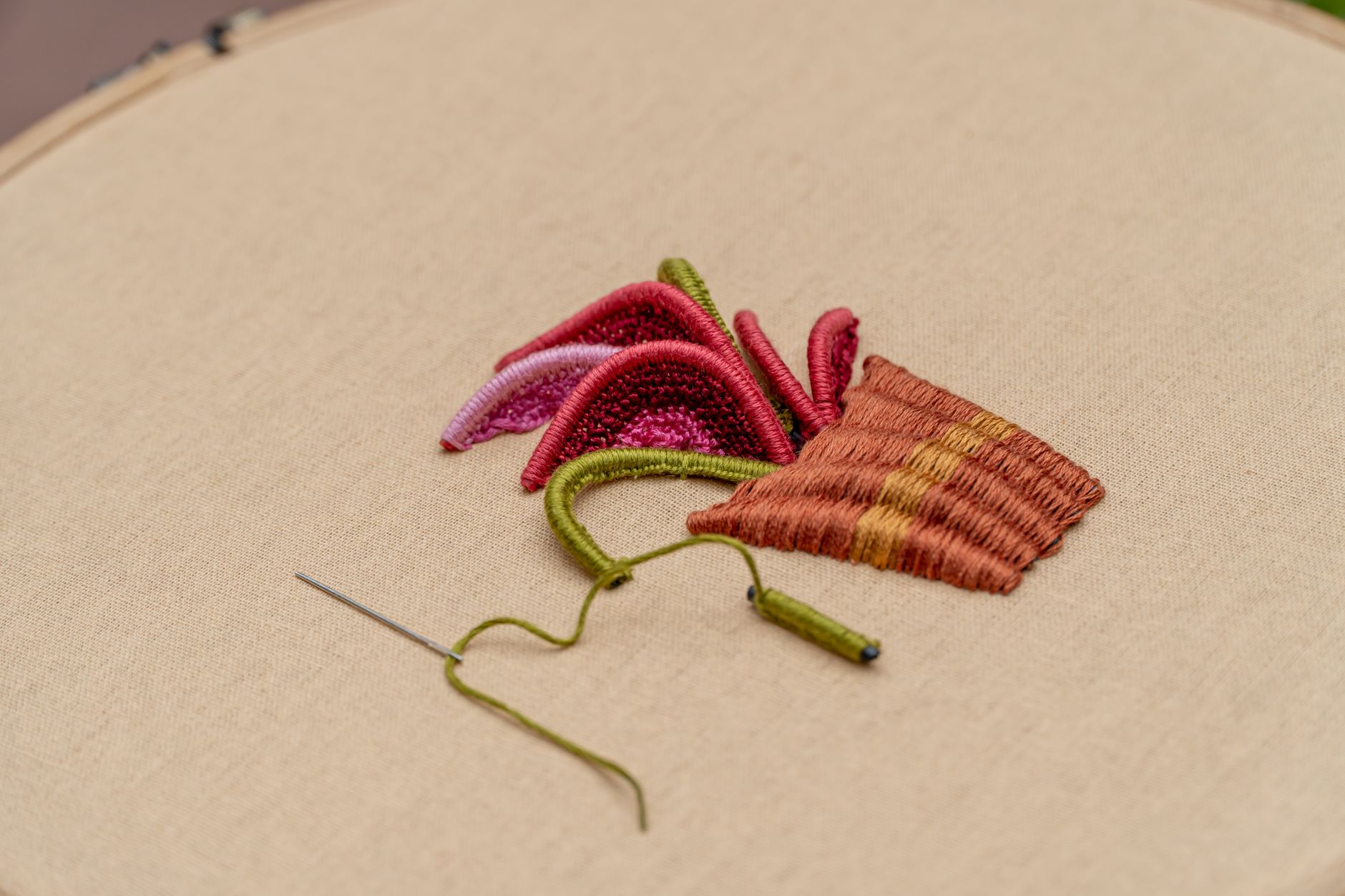 Hands working on traditional embroidery with colorful thread on fabric