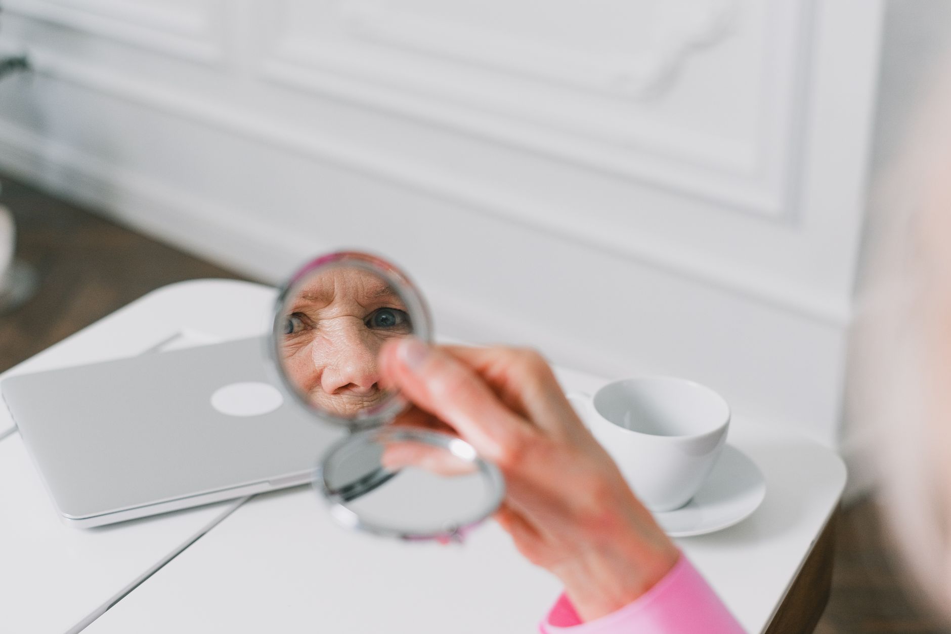 Woman looking at her reflection in a mirror, soft natural light