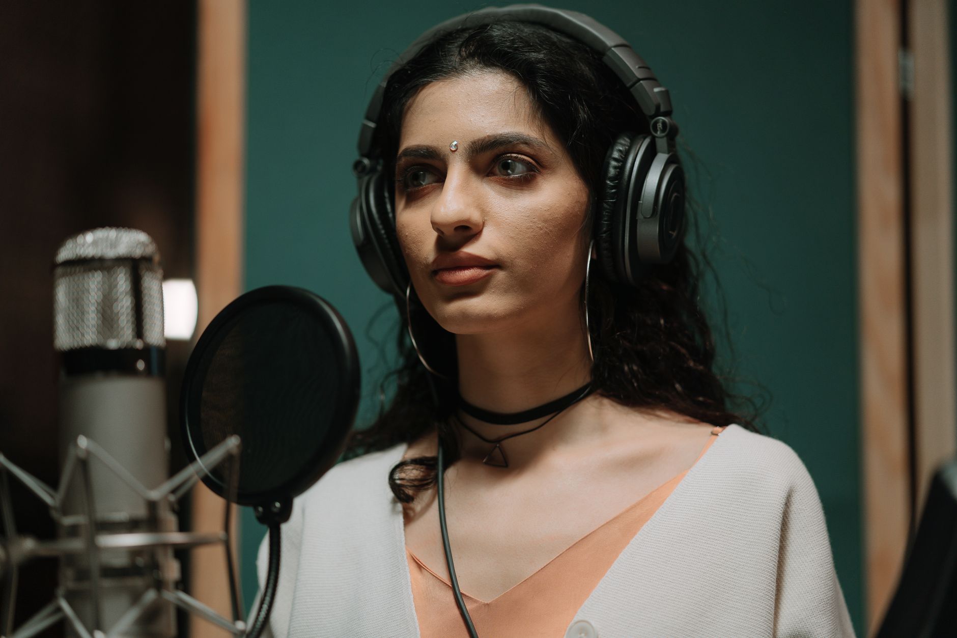 A musician in a recording studio, headphones on, working on a new sound