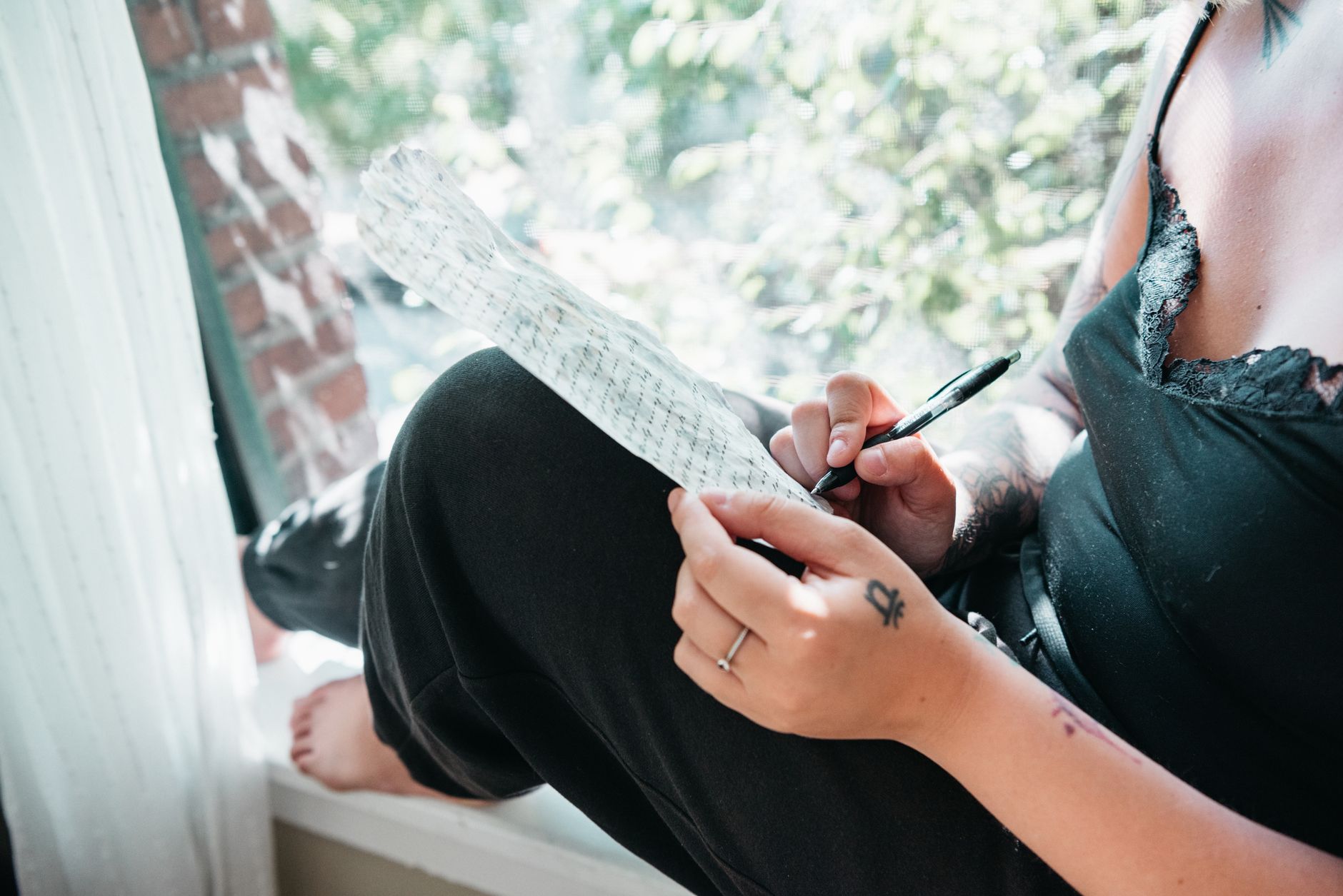 Person writing in a journal by a window during a quiet reflective moment
