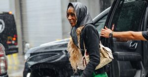 A fashion week attendee walking in the rain on a New York City street carrying an umbrella