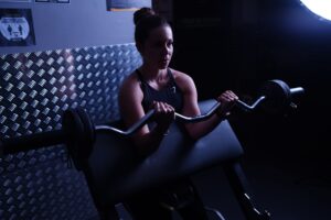 A Breast Cancer Diagnosis at 26, and the Barbell That Followed A young woman preparing to lift a barbell in a gym setting