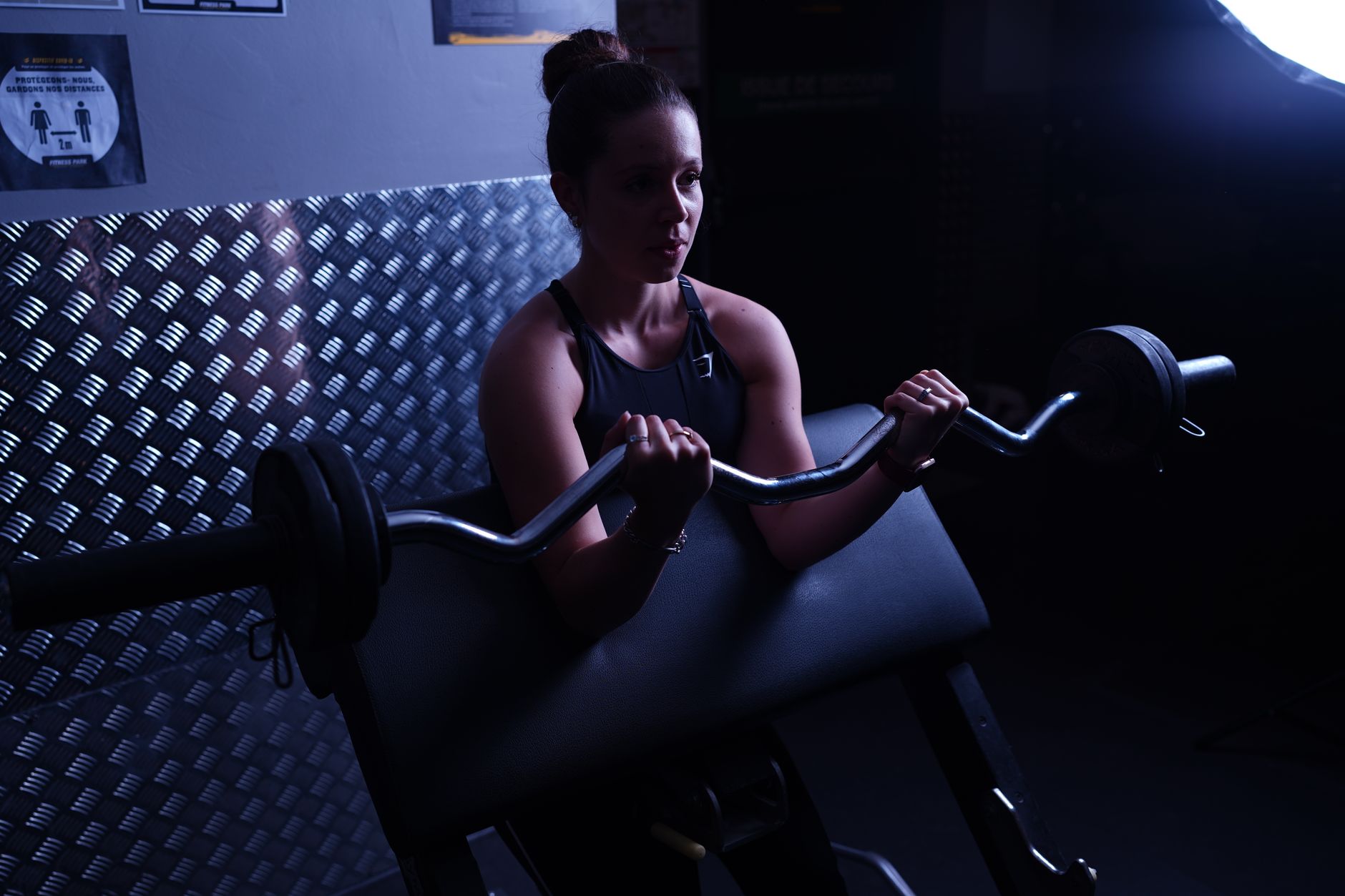 A young woman preparing to lift a barbell in a gym setting