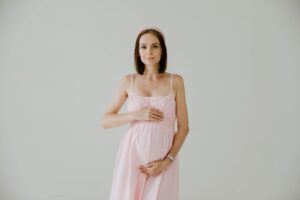 Woman in a soft empire-waist dress with minimal styling against a neutral background