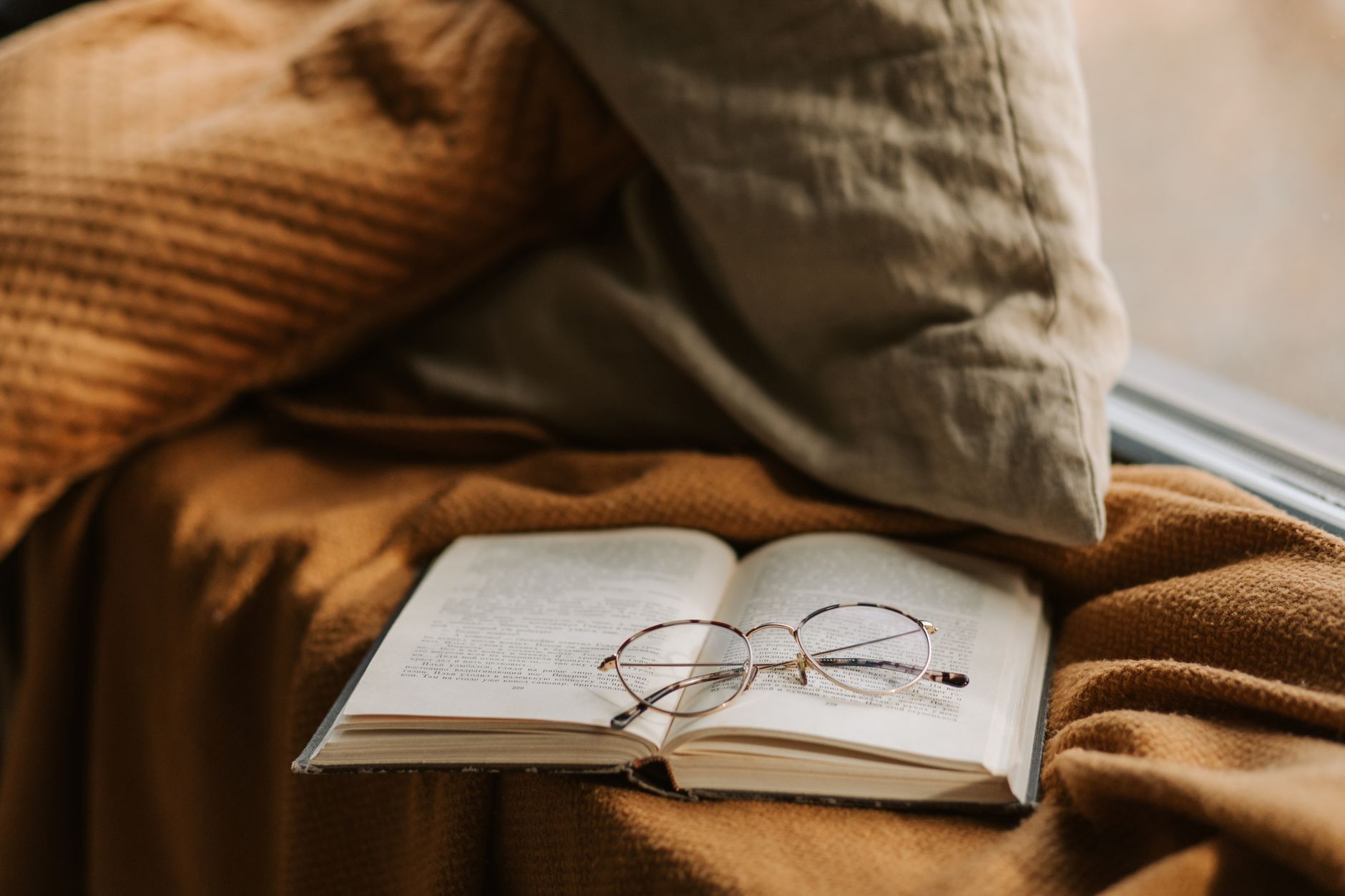 Open book resting on a blanket in warm indoor lighting