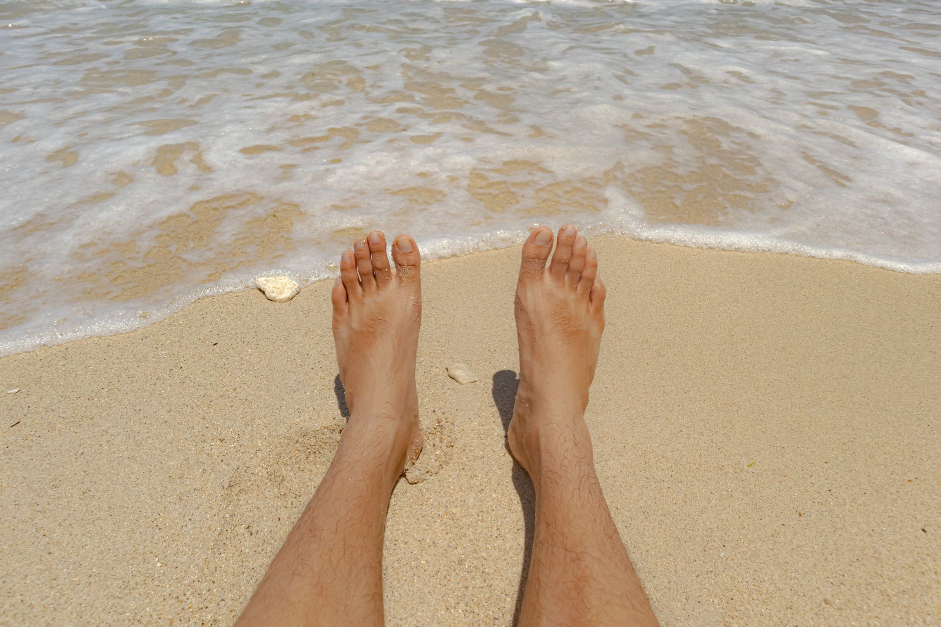 Two people relaxing on a beach with drinks, enjoying a slow vacation afternoon