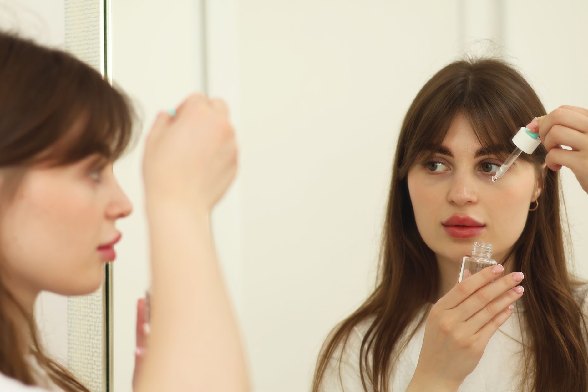 Woman applying skincare products at a bathroom mirror