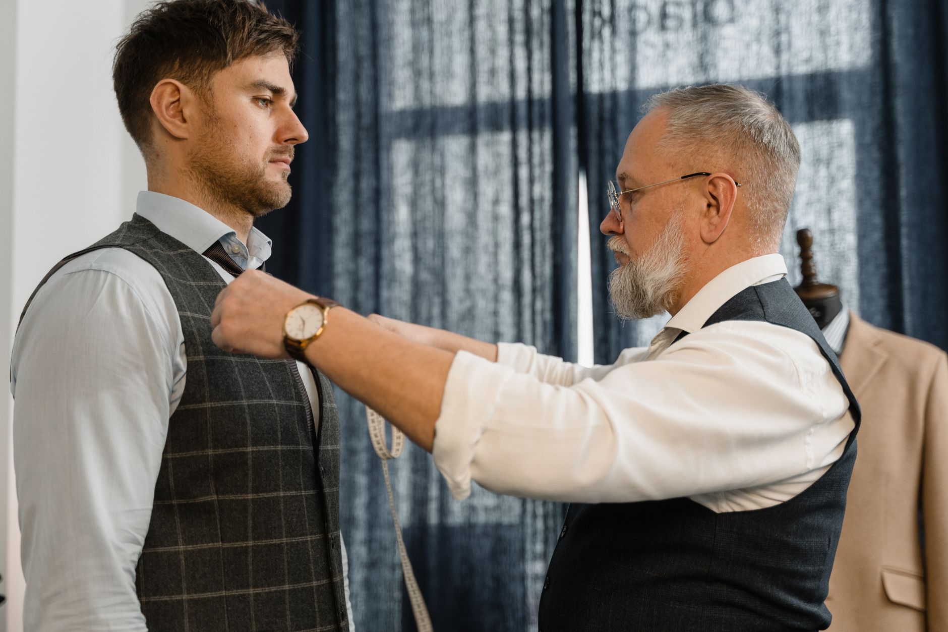 A tailor adjusting the fit of a garment on a person in a studio setting