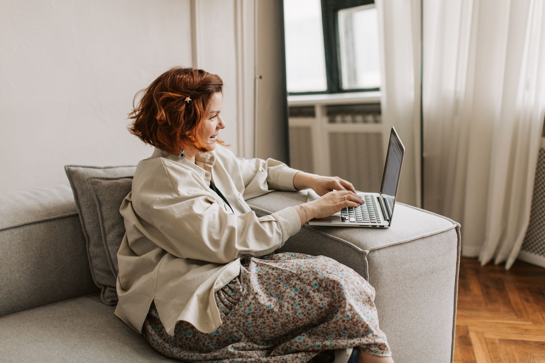 Woman in comfortable clothing working from home at a desk near a window