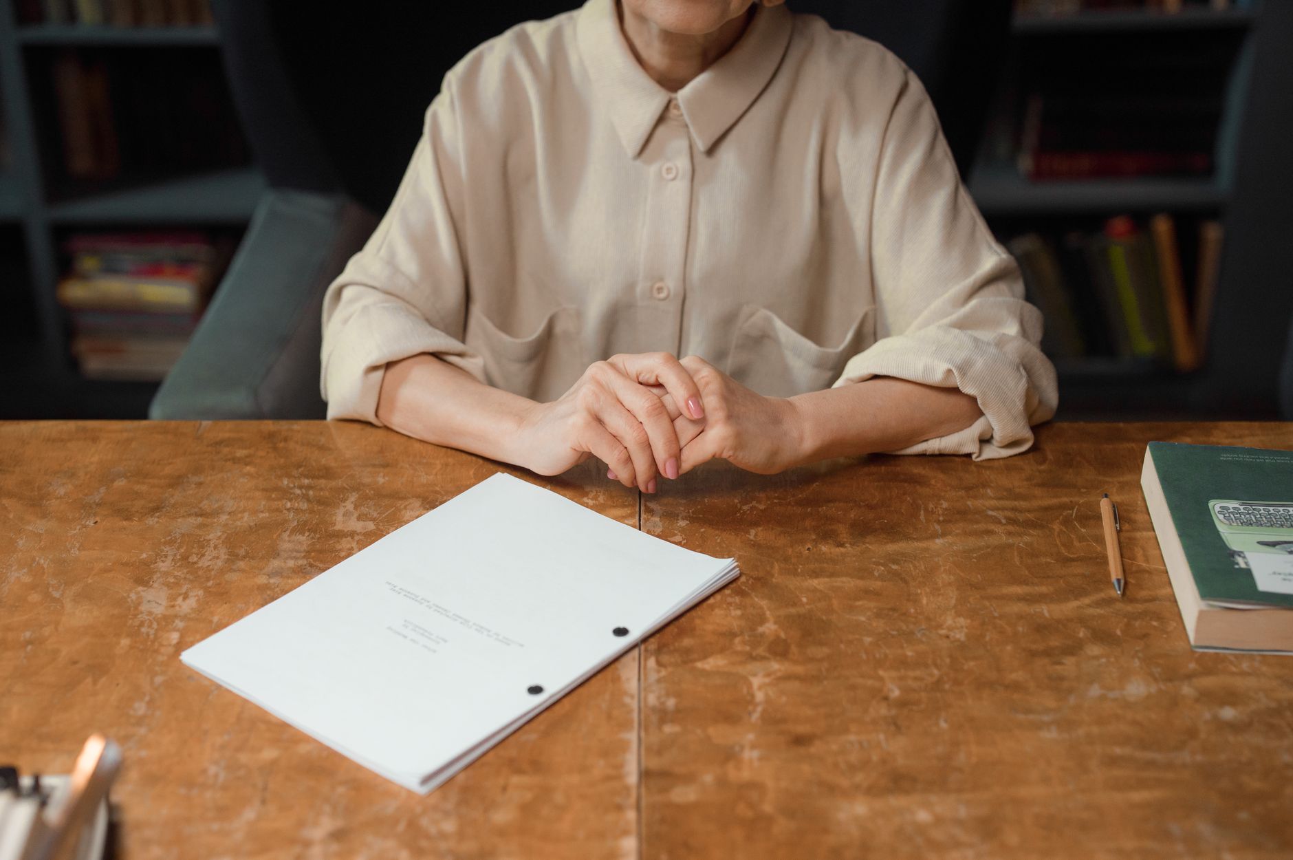 Woman reading papers at a desk in a dimly lit room