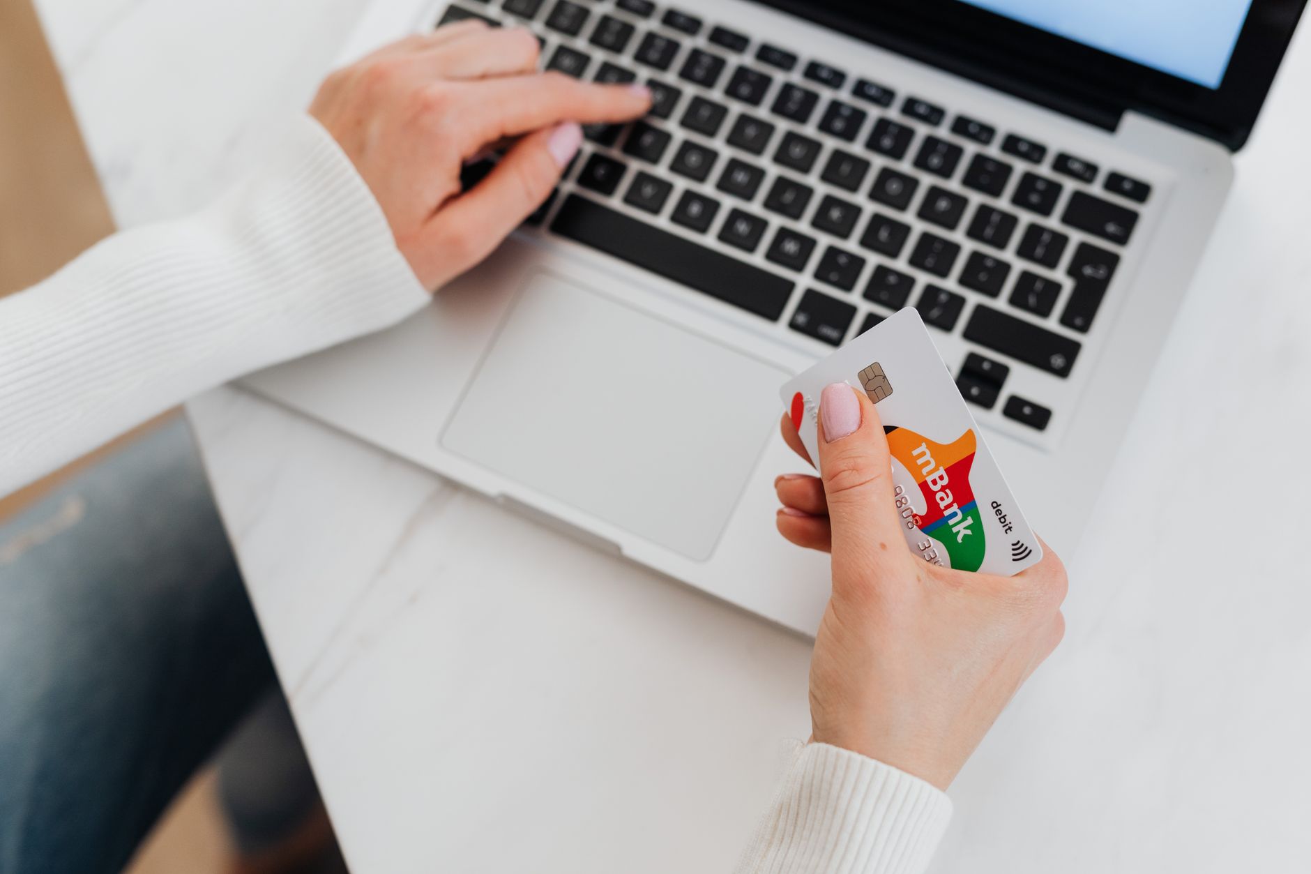 Person browsing online shopping on a laptop with a credit card nearby