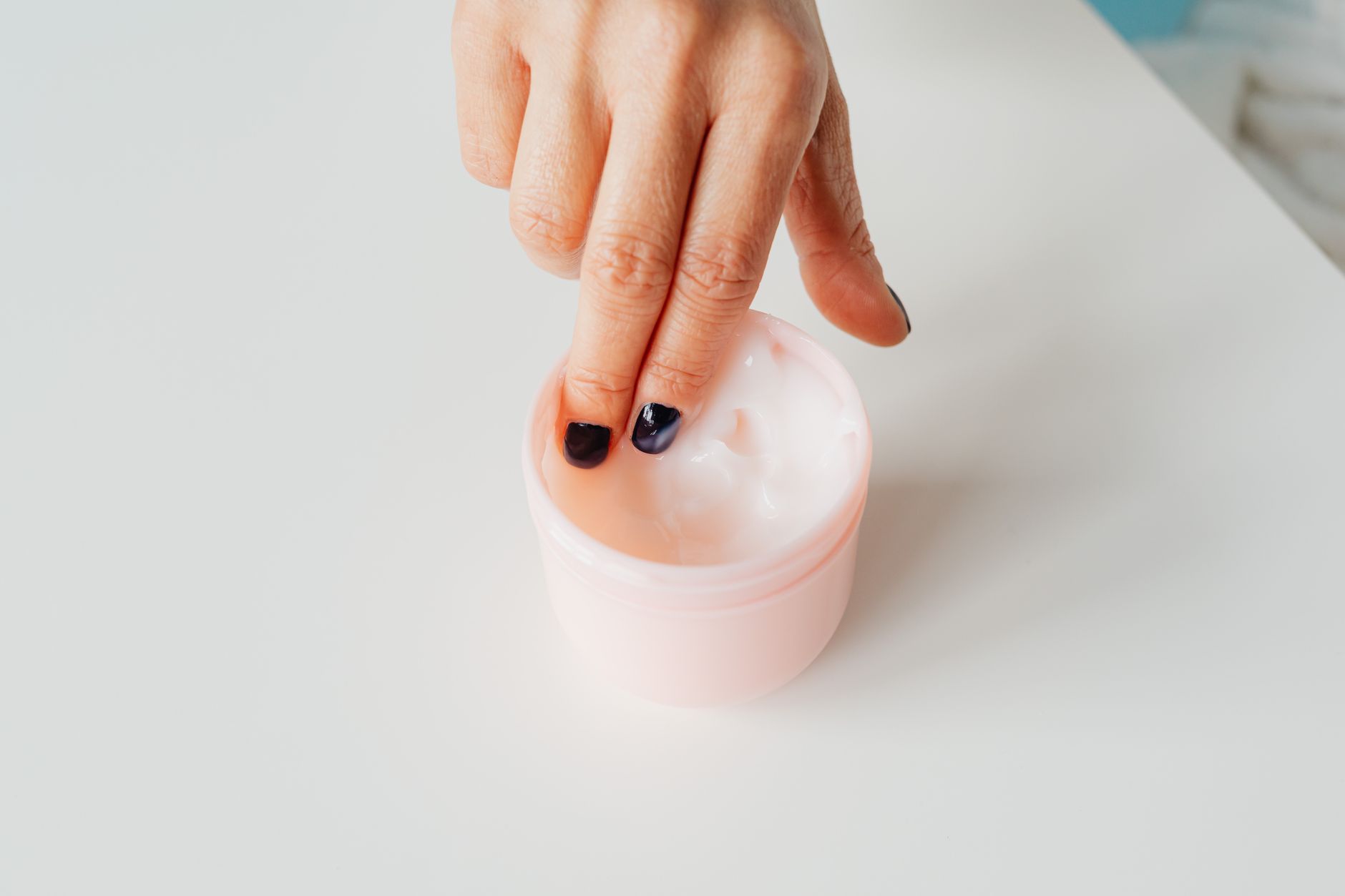 Woman applying face cream moisturizer in soft natural light