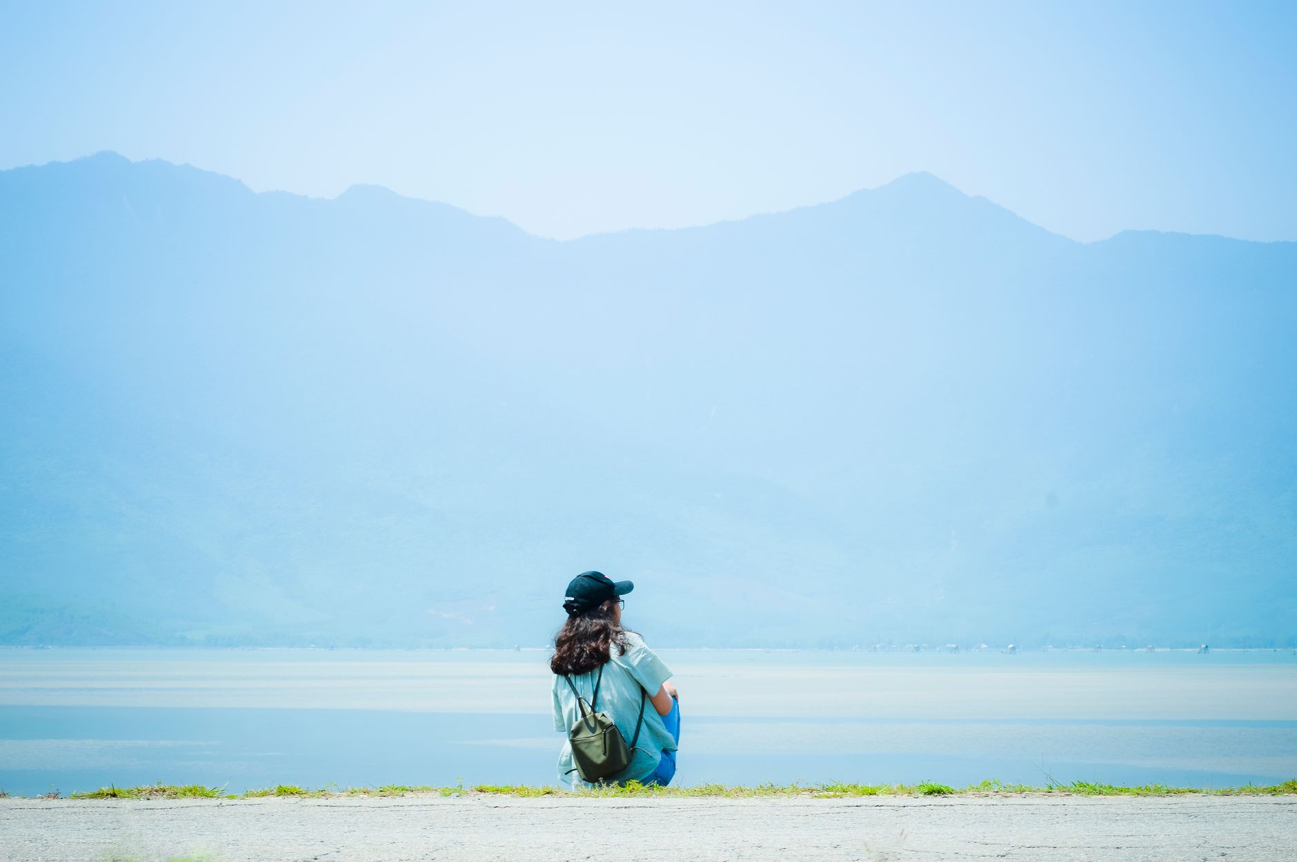 A person sitting alone in a quiet indoor space, looking downward