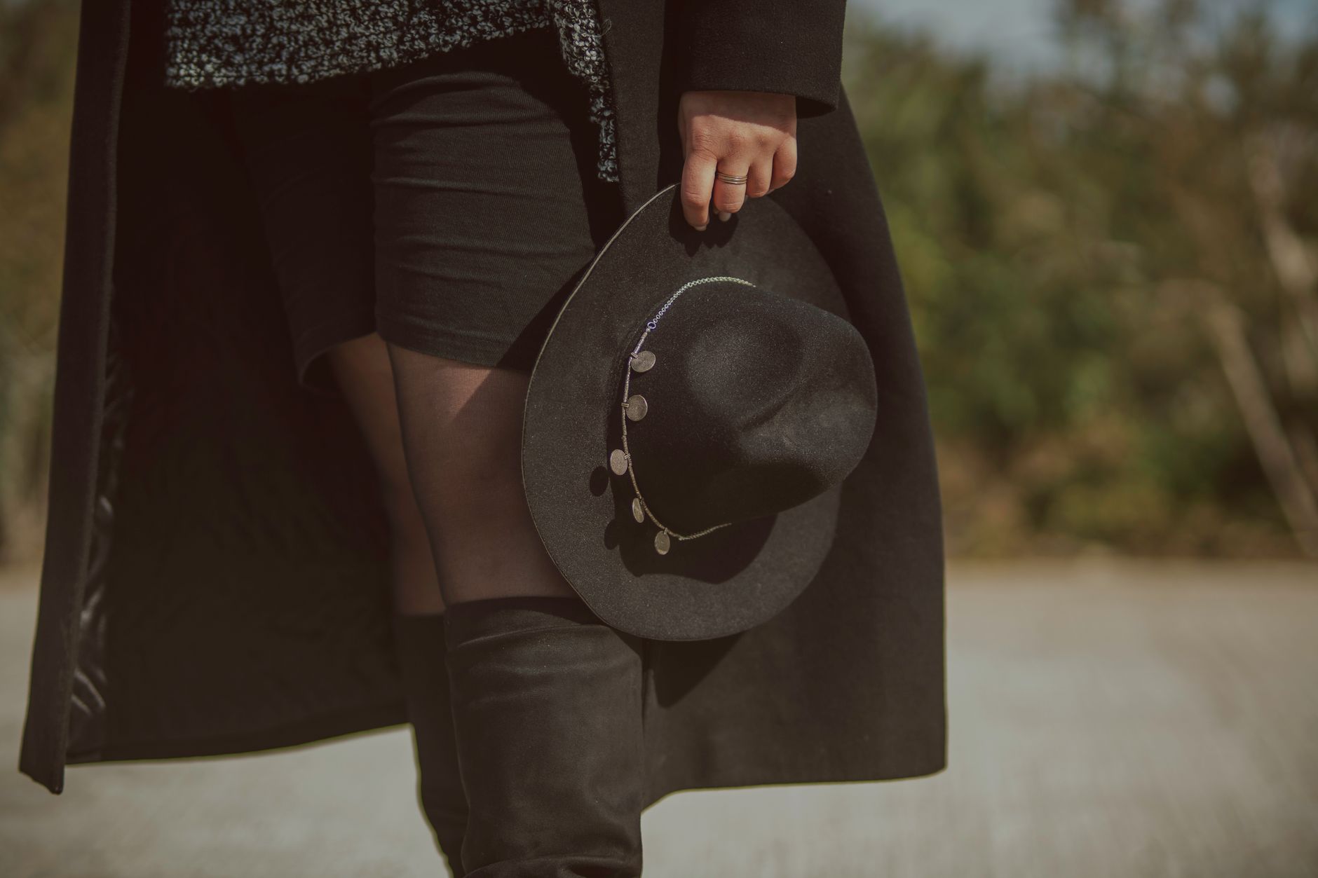 Full-length shot of a woman in tonal brown fall clothing including boots, coat, and knitwear