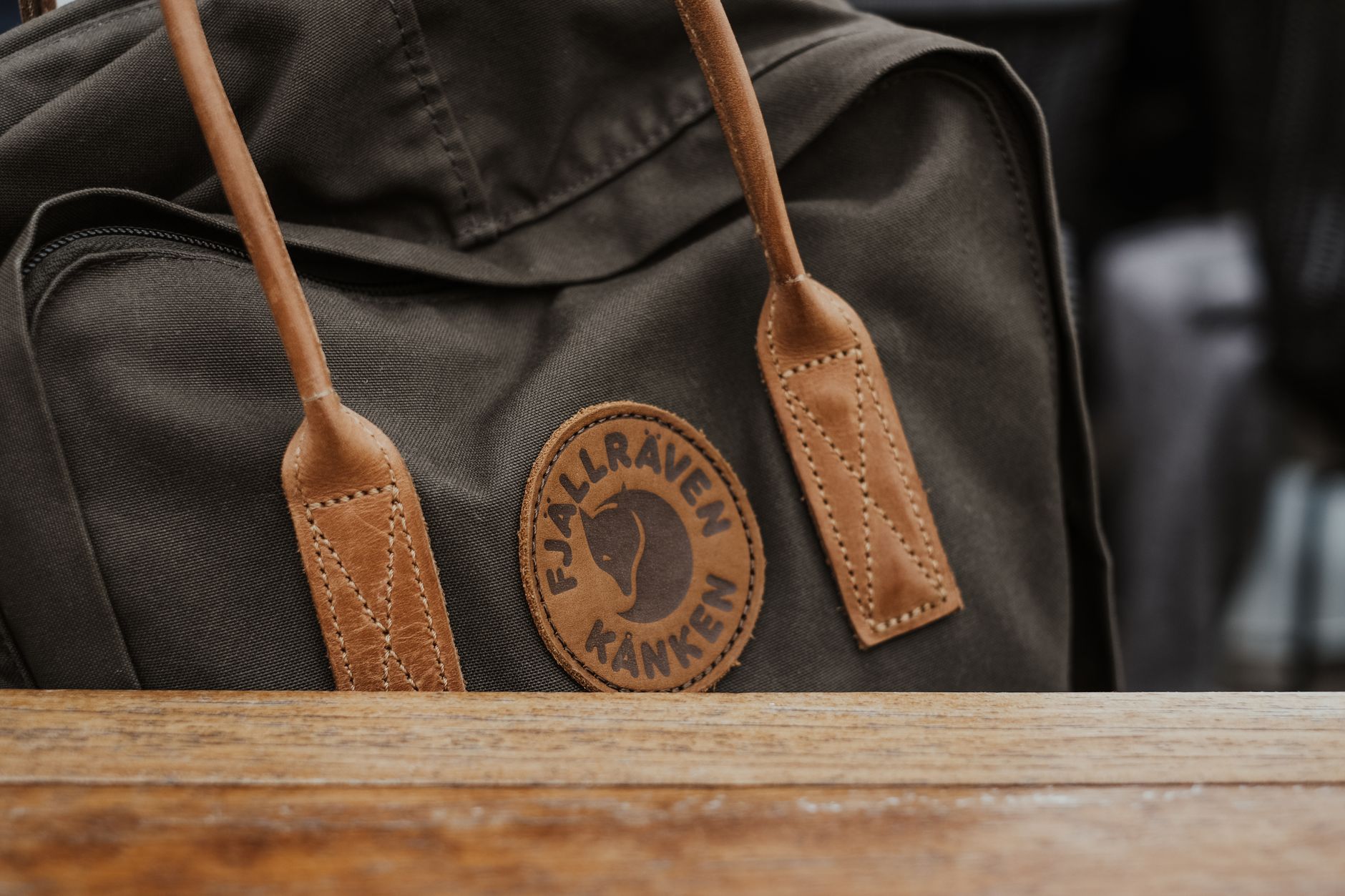 A structured leather backpack resting against a neutral wall