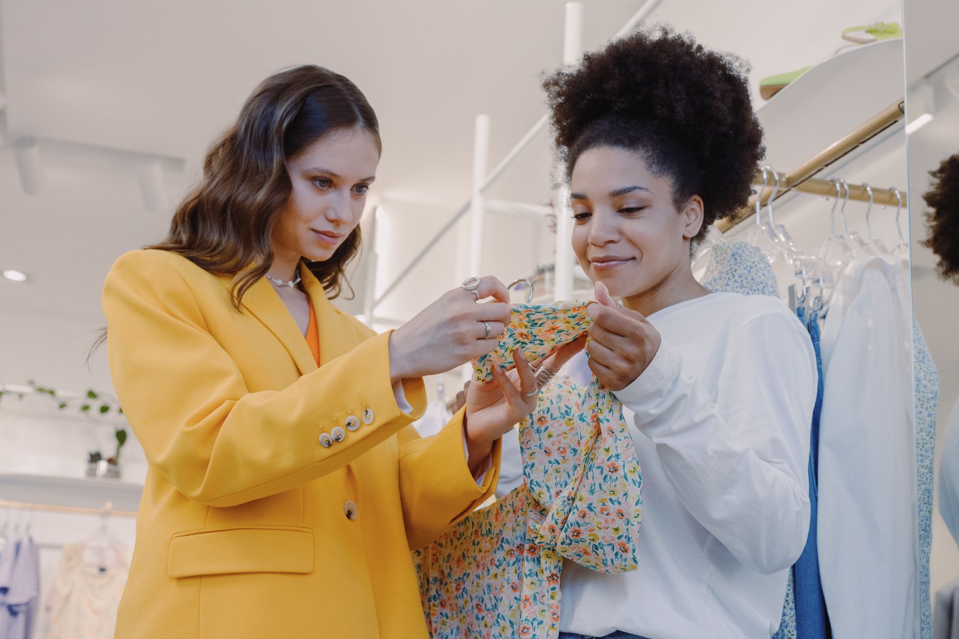 Two women browsing jackets on a rack in a clothing store
