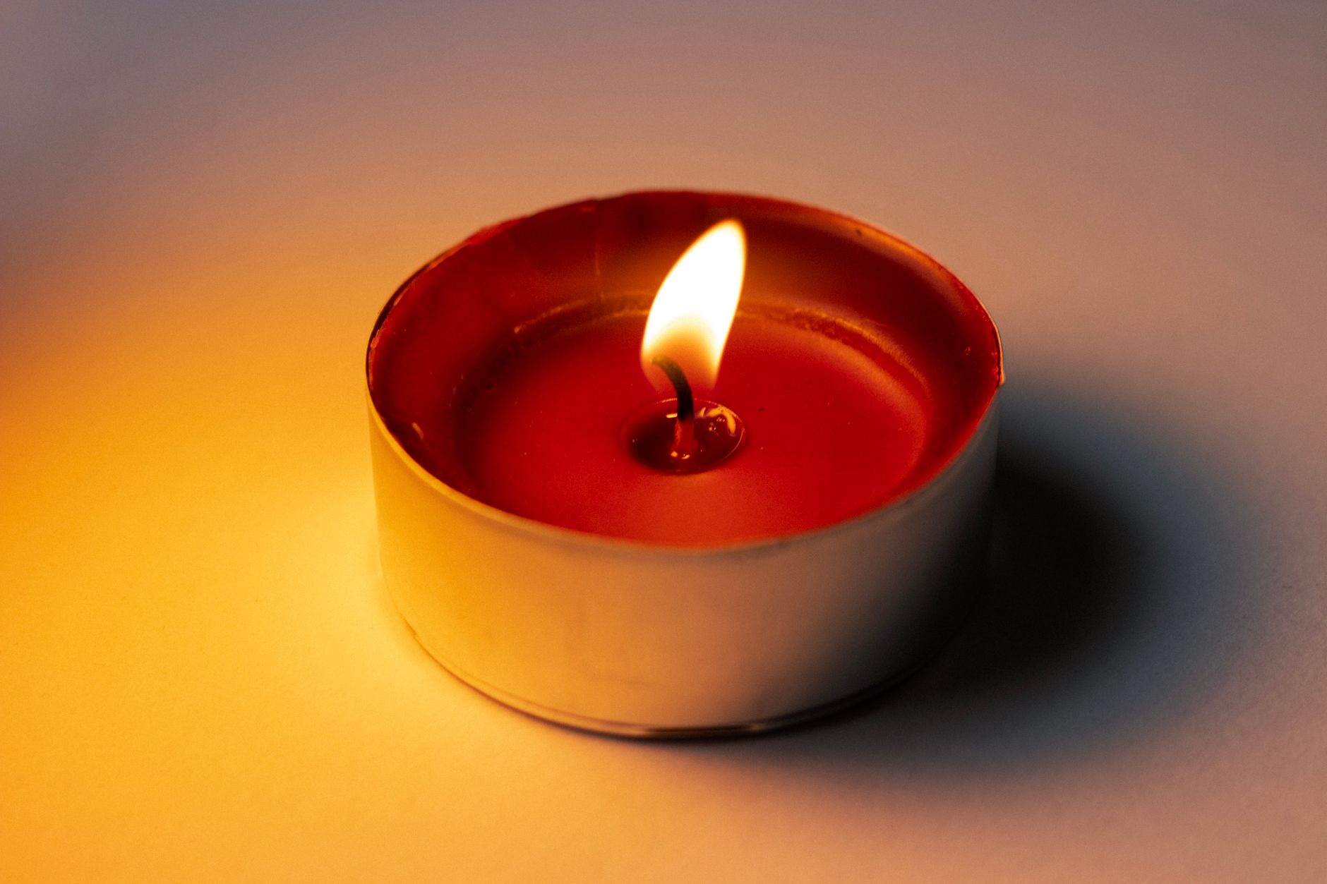 Single lit candle with soft flame against a dark background