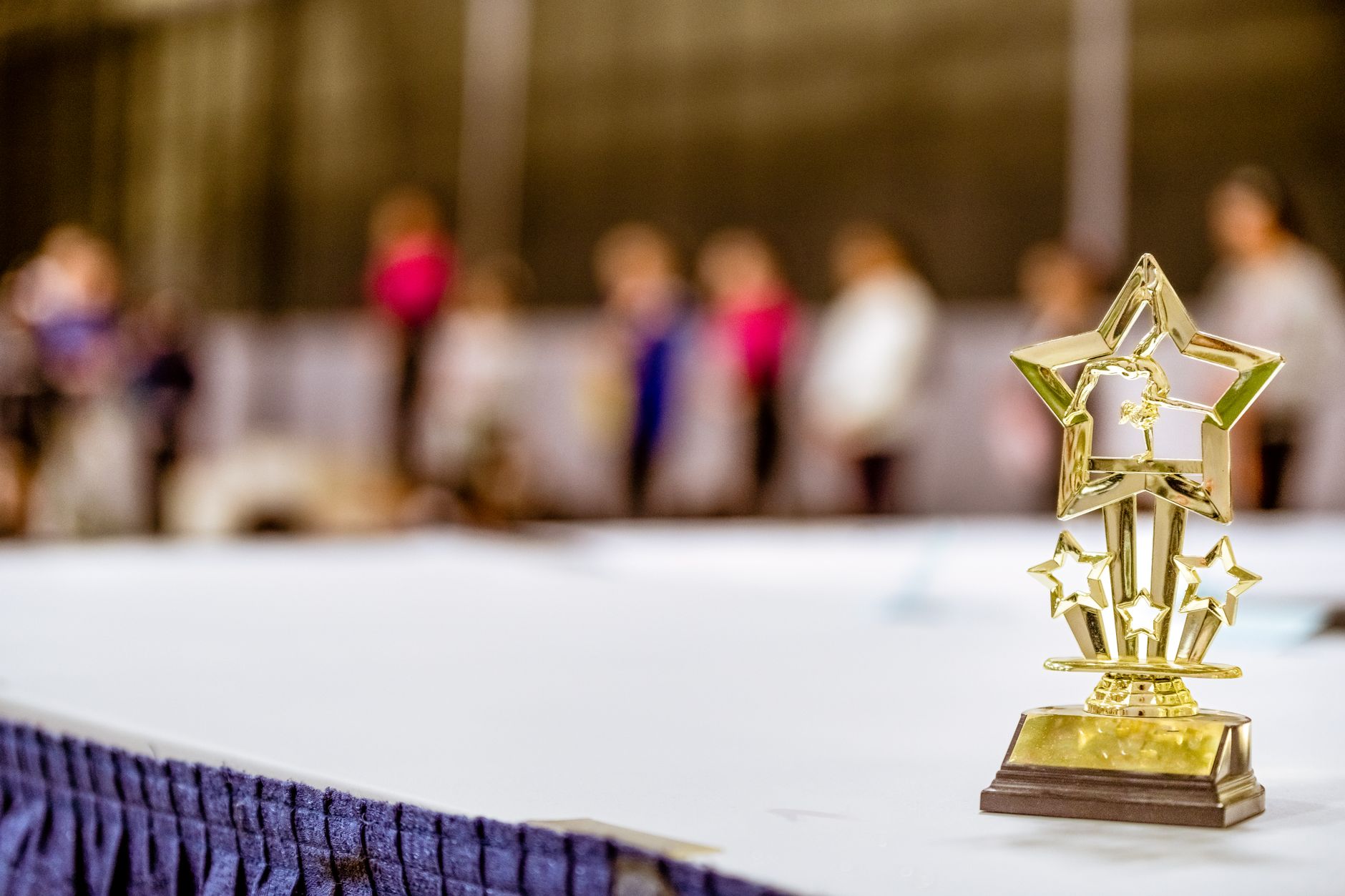 A shiny trophy on a stage under dramatic spotlight at a live event