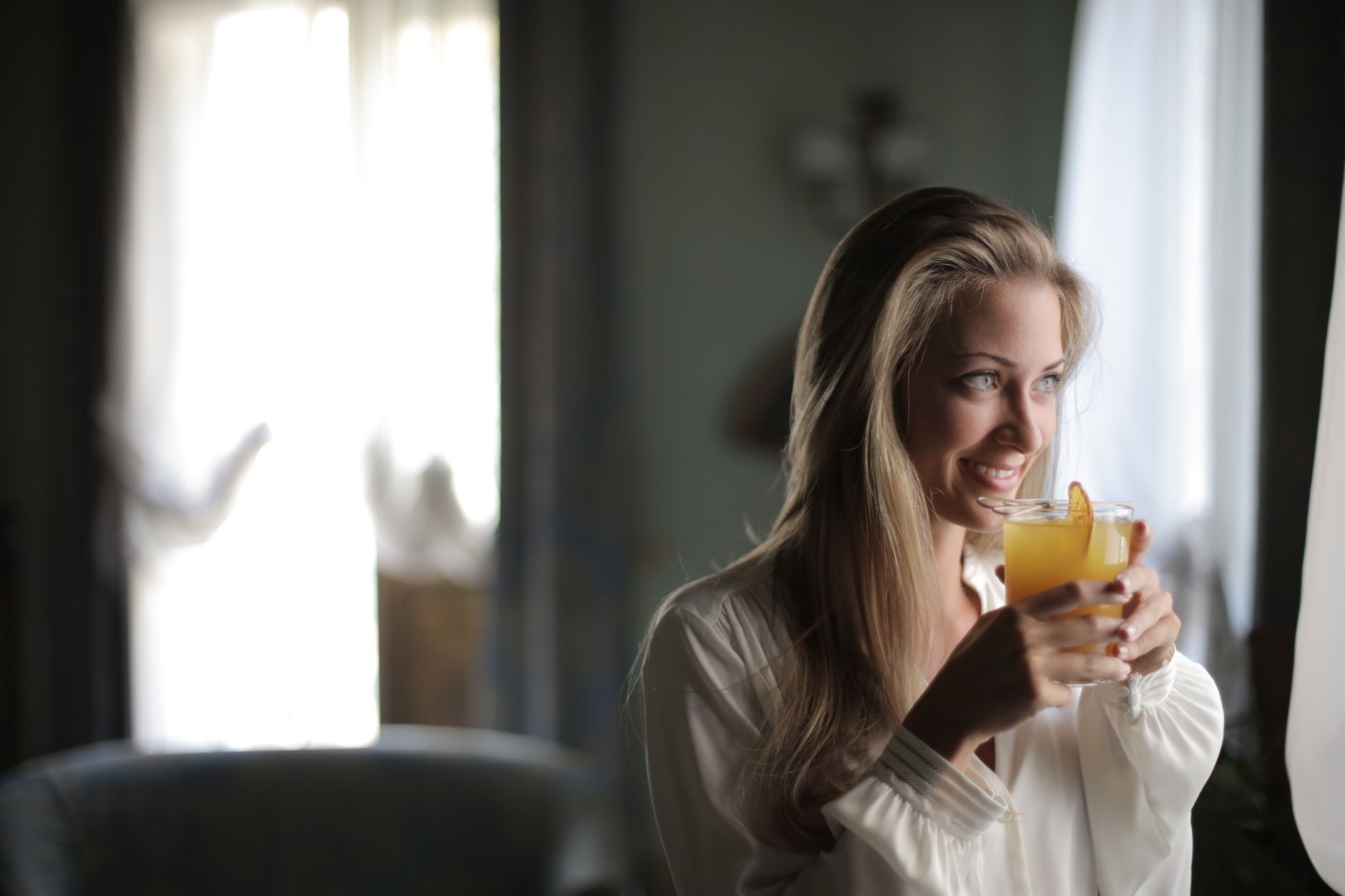 Small glass of amber-colored health drink on a wooden surface beside fresh ingredients
