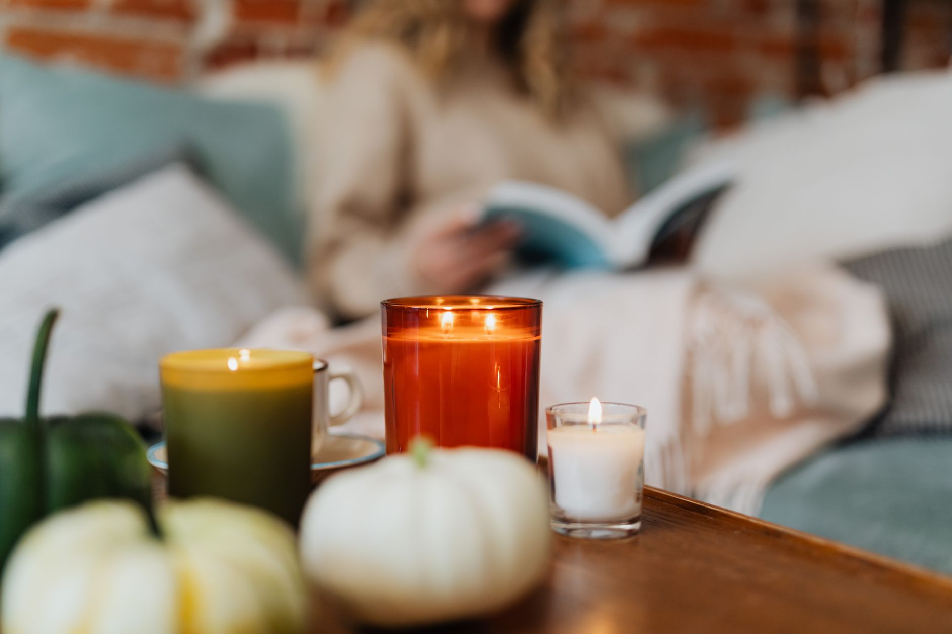 Lit candles arranged on a surface with dried autumn leaves in warm ambient light