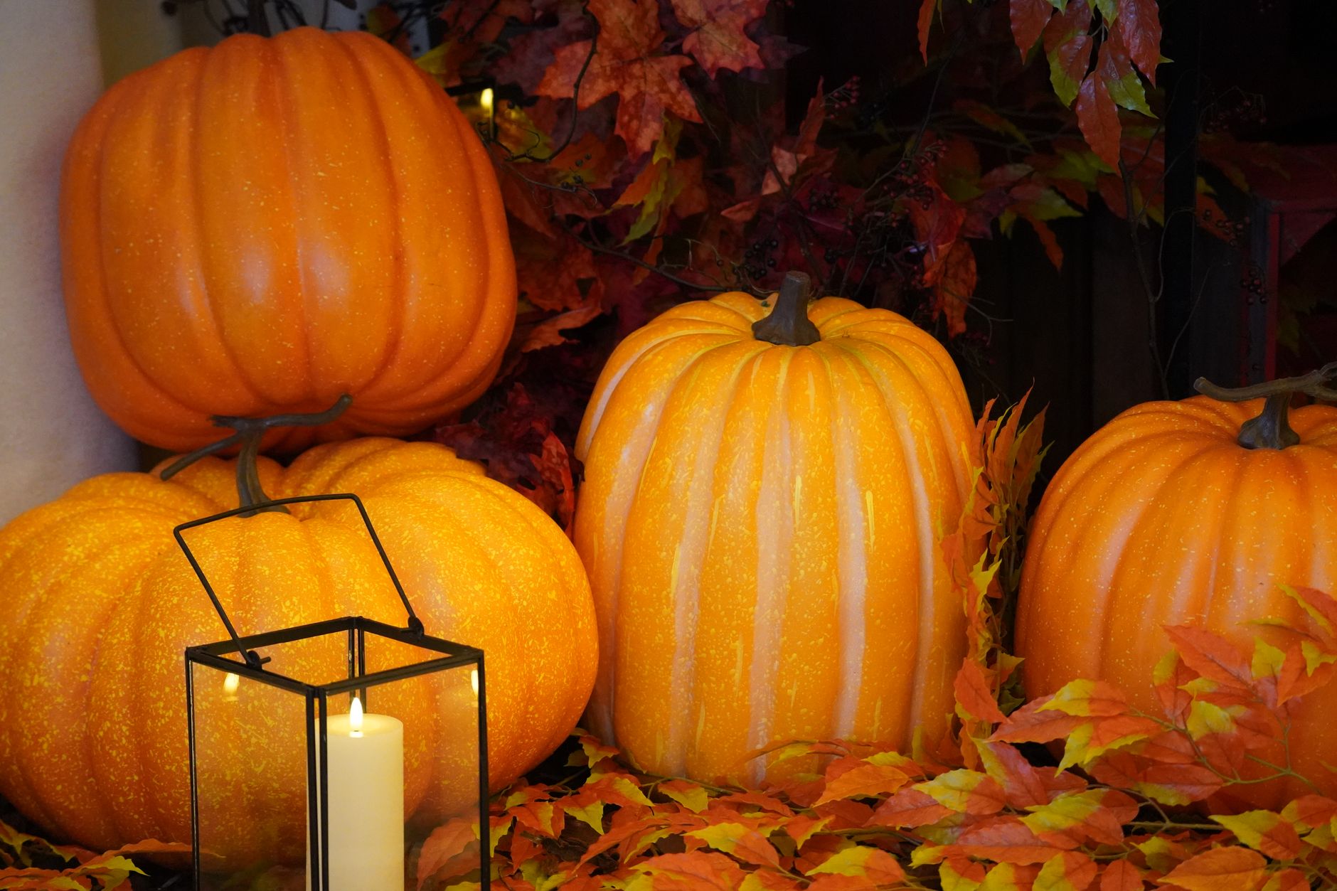Lit candles and autumn leaves arranged on a wooden surface for Halloween
