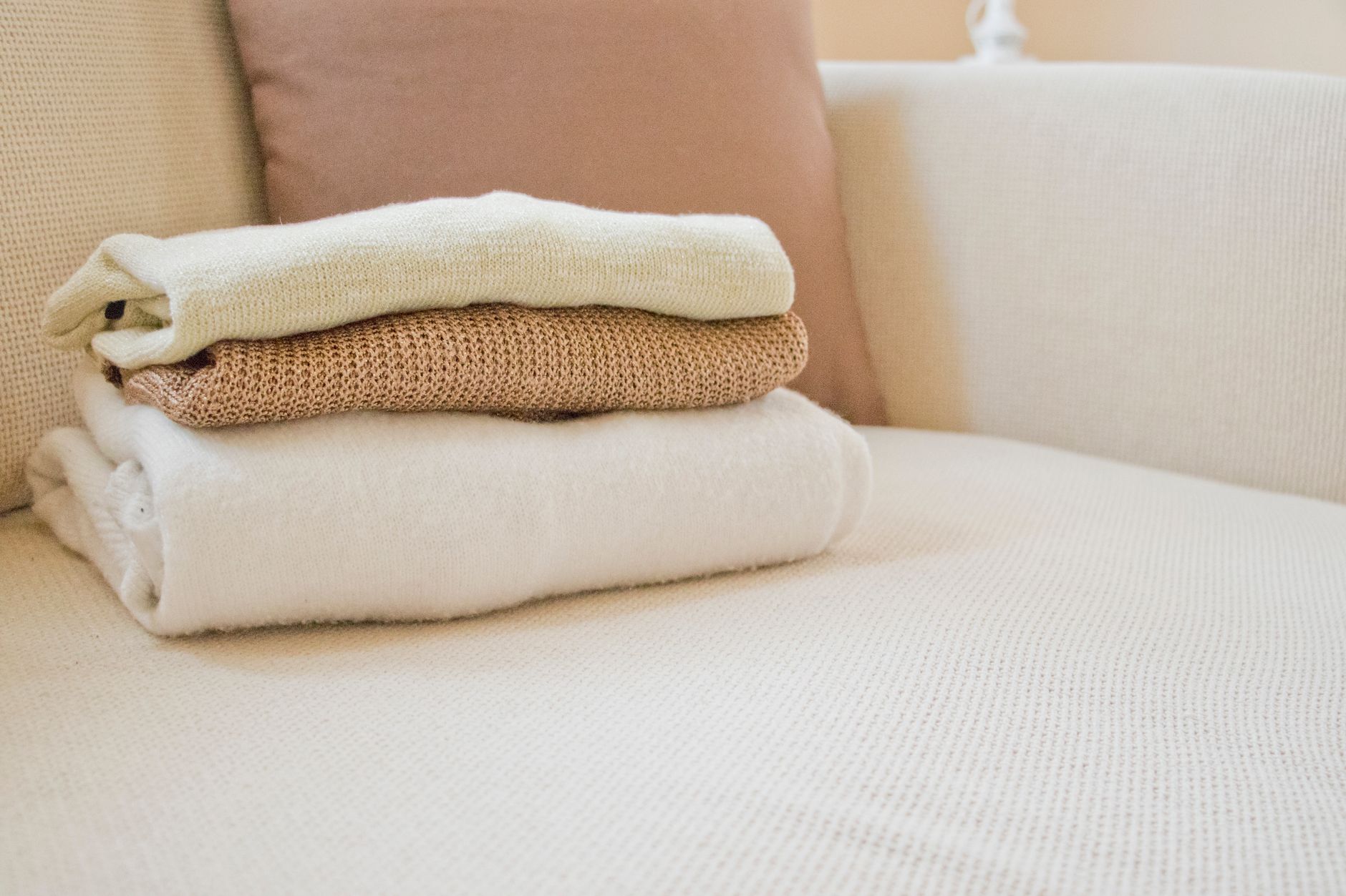 Neatly folded cable knit sweaters and loungewear in neutral tones stacked on a shelf