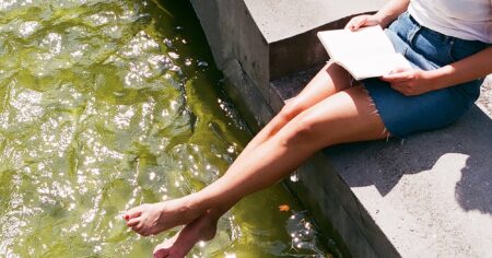 Woman reading a paperback book alone in soft natural light