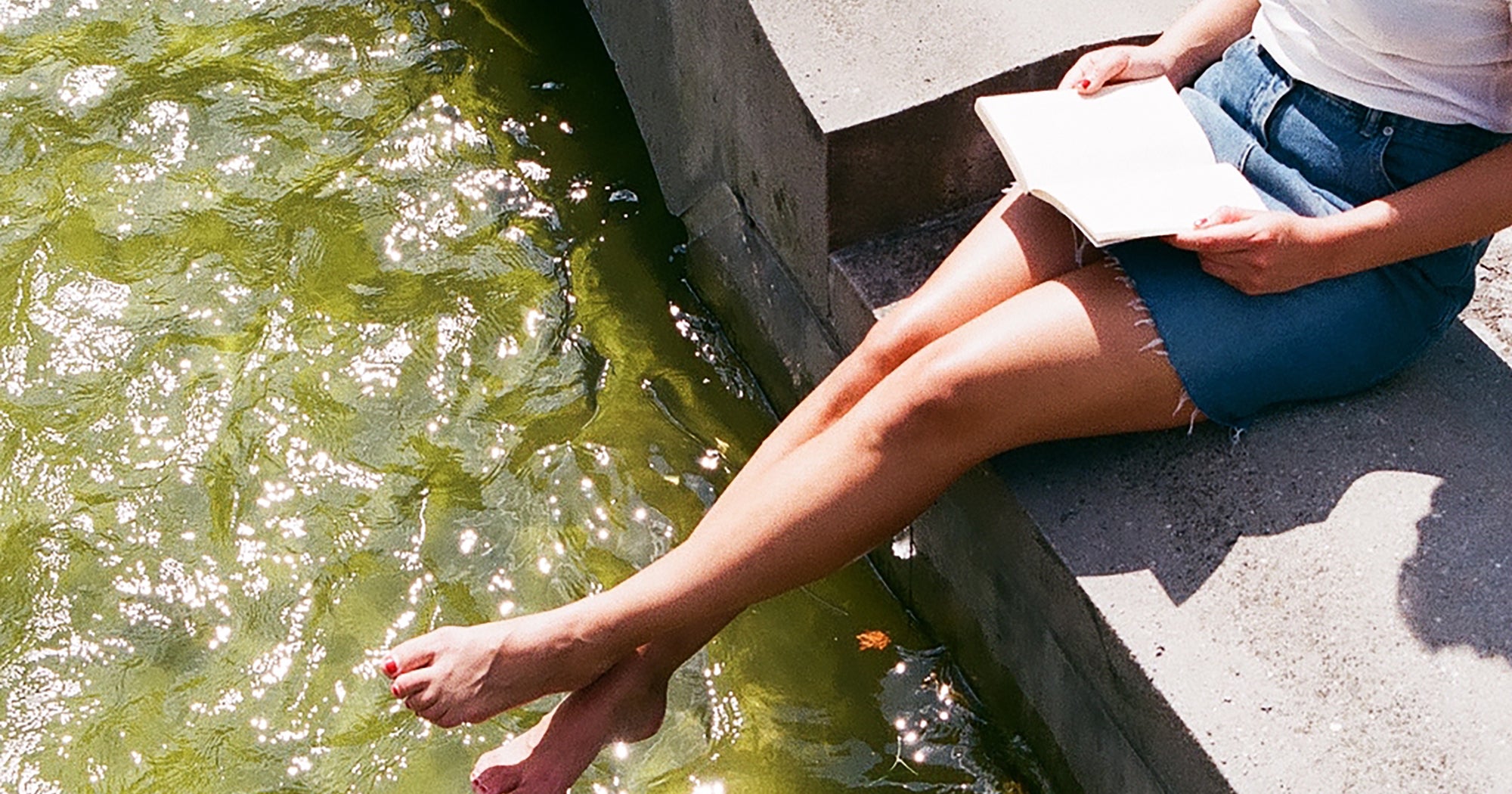 Woman reading a paperback book alone in soft natural light