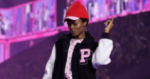 Models walking a fashion runway in bold, sporty outfits under dramatic stage lighting