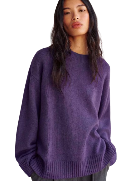 Woman wearing a vibrant purple sweater styled with contrasting separates